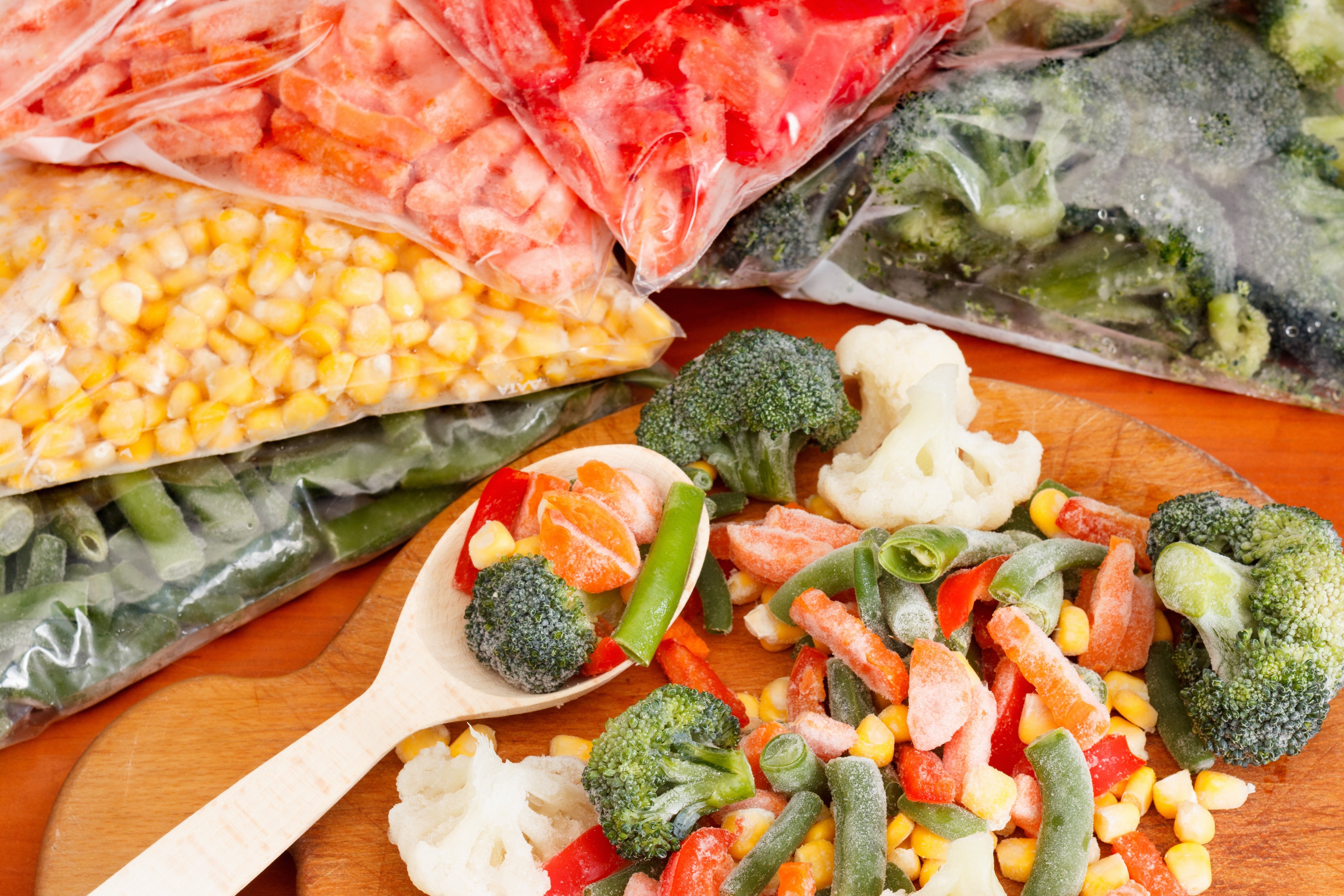 Frozen vegetables on cutting board and plastic bags. | Source: Shutterstock