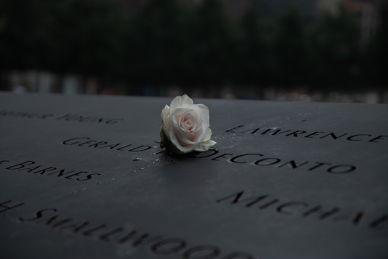 A white rose on a 911 memorilal headstone | Photo: Pexels