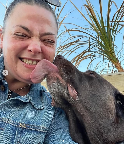 Lisa Armstrong beams as Hurley affectionately licks her face in a playful selfie shared on June 14, 2021, capturing a tender moment between the make-up artist and her beloved chocolate Labrador. | Source: Instagram/lisaarmstrongmakeup