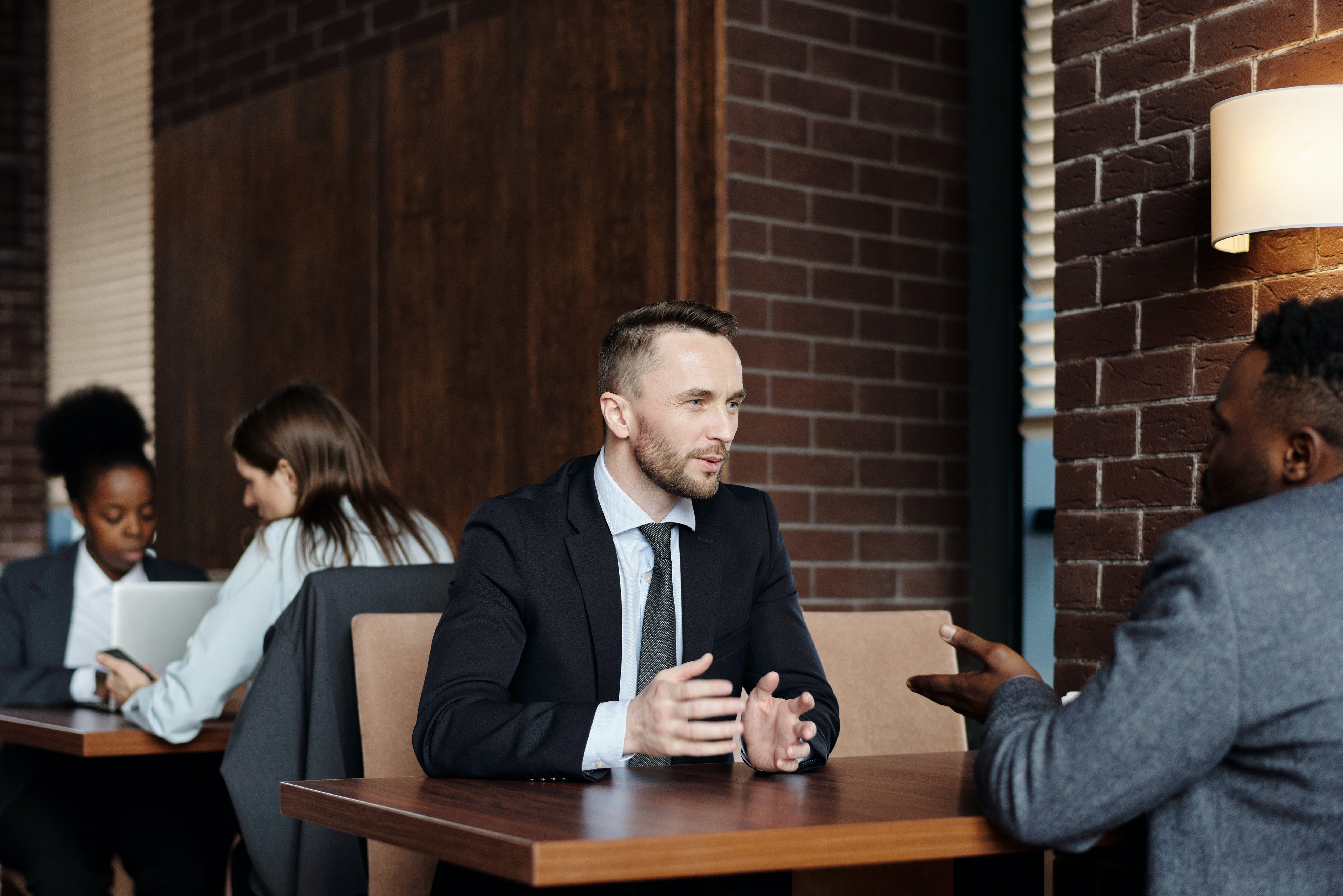 Un hombre vestido de traje hablando con otro hombre en un café. | Foto: Pexels