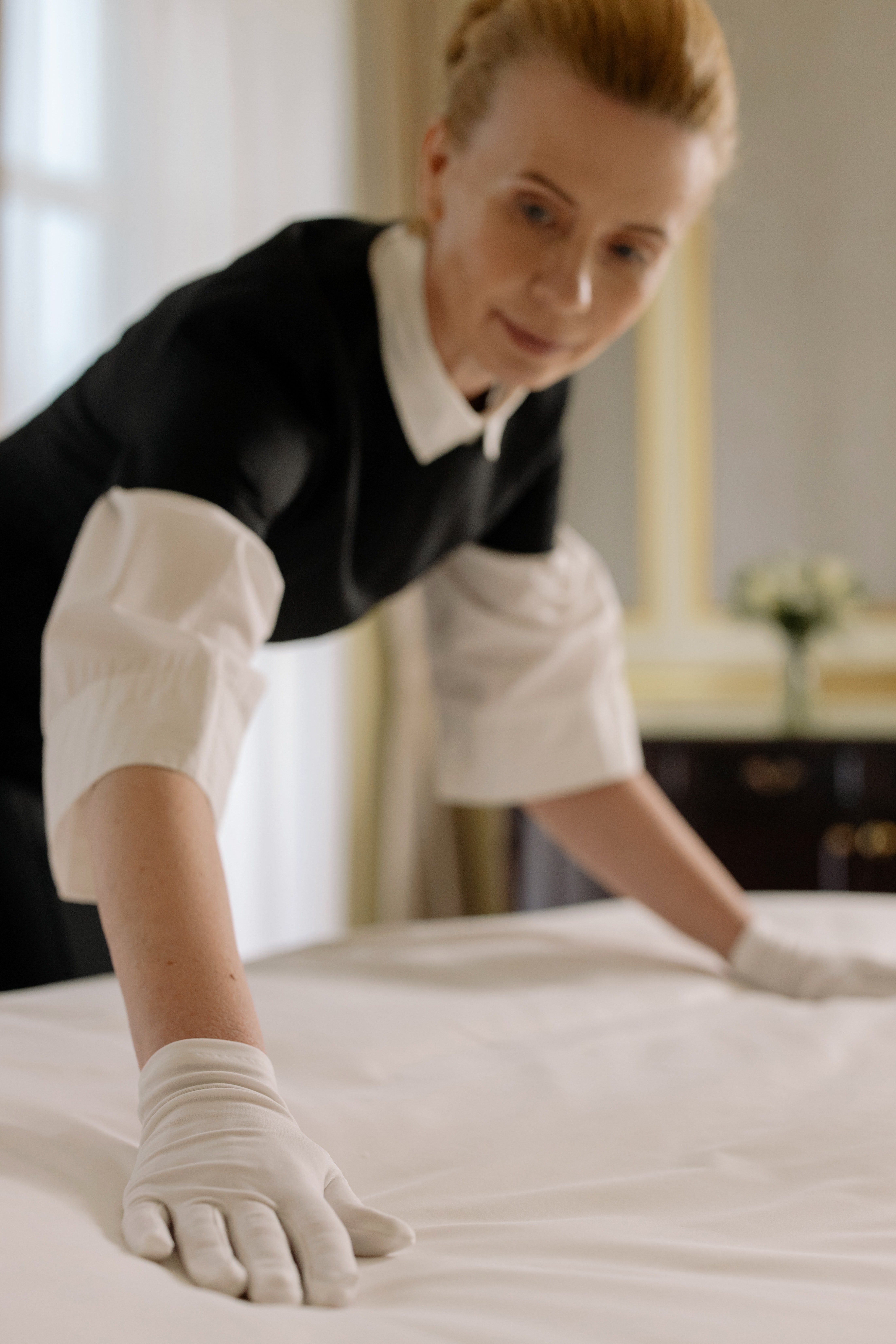 Una trabajadora doméstica arreglando una cama. | Foto: Pexels
