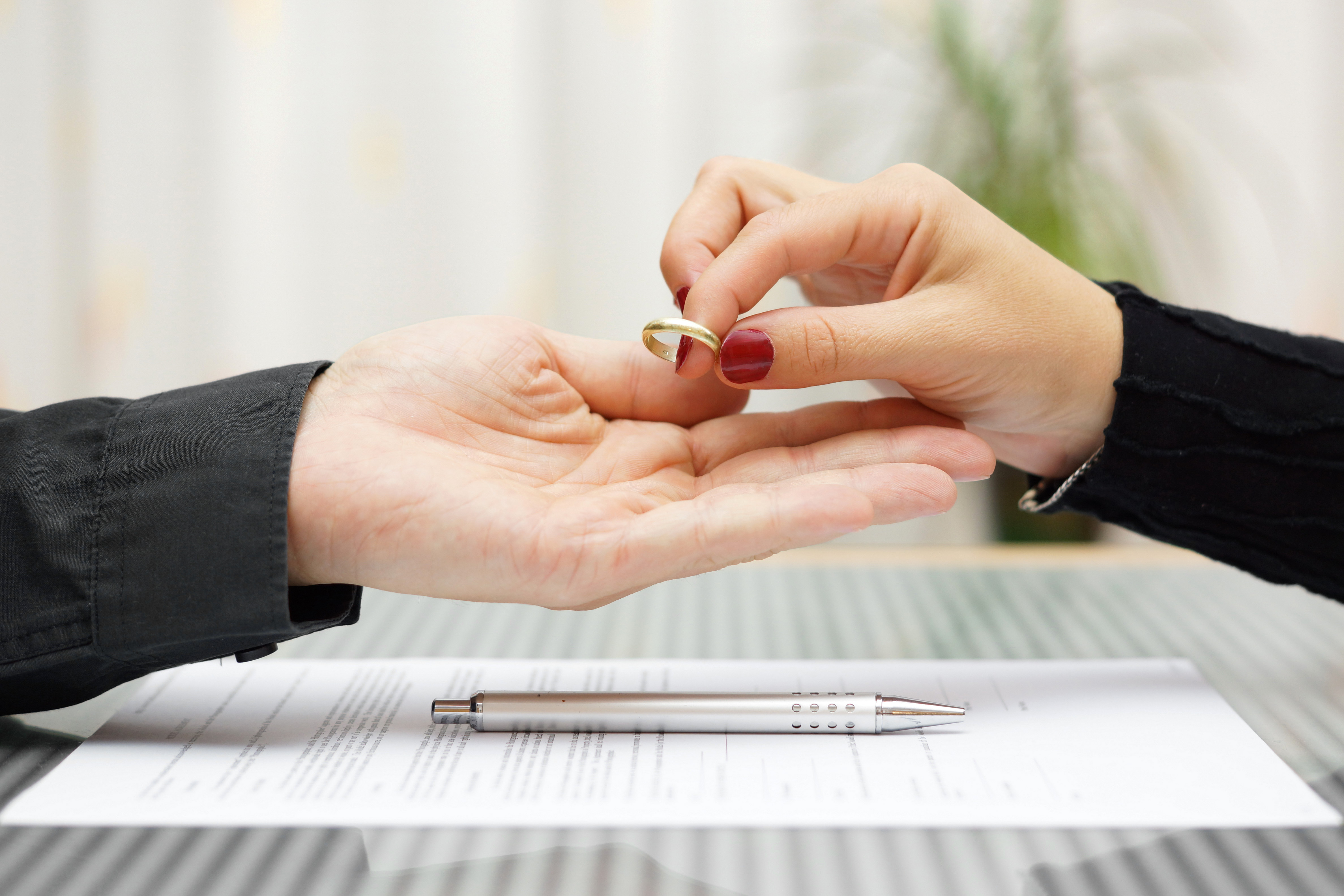 A woman returning her wedding ring to a man over legal documents | Source: Shutterstock