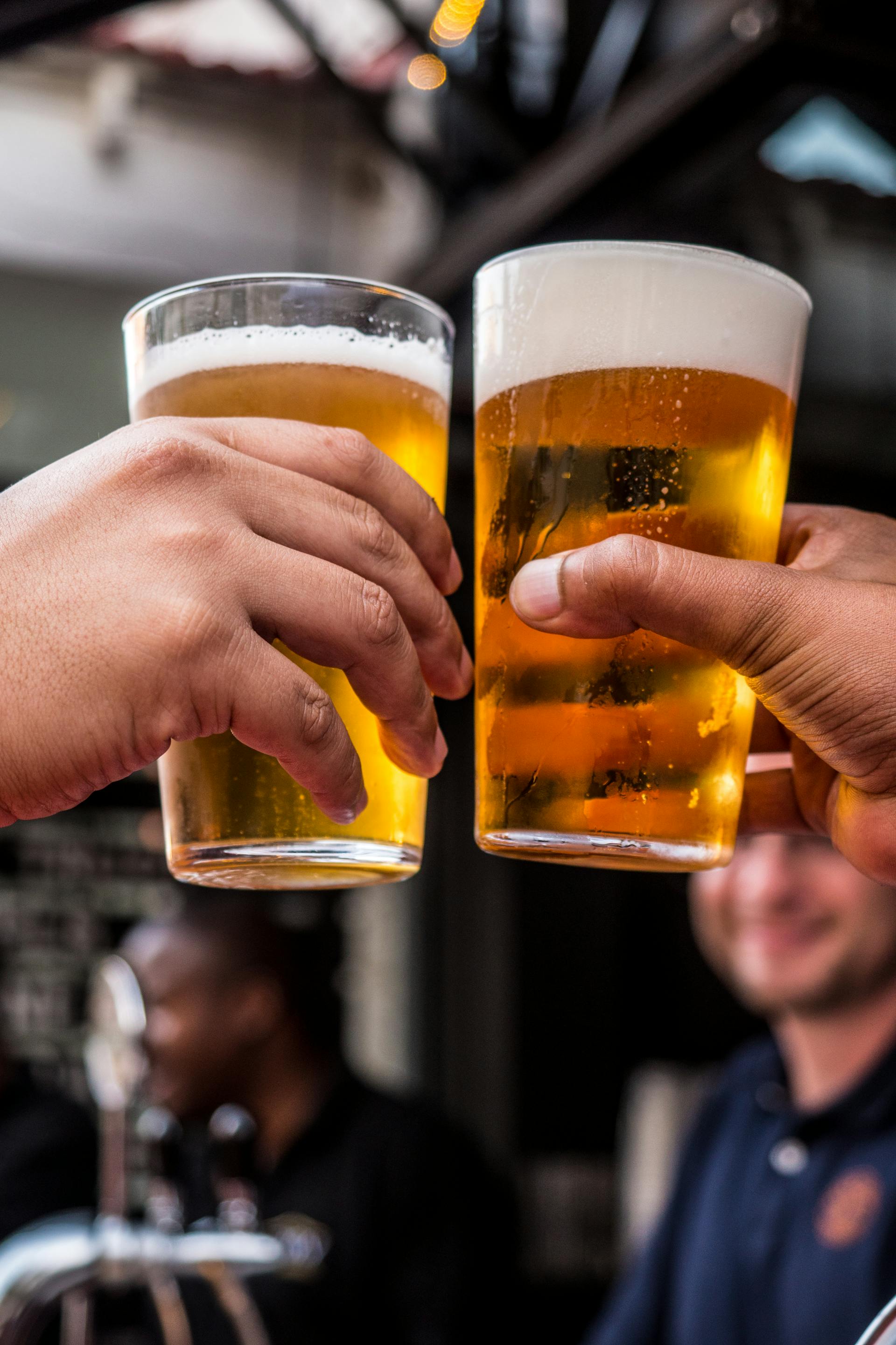 Two persons holding glasses filled with beer | Source: Pexels