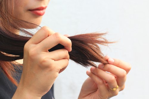 Frau betastet ihre Haarspitzen | Quelle: Shutterstock