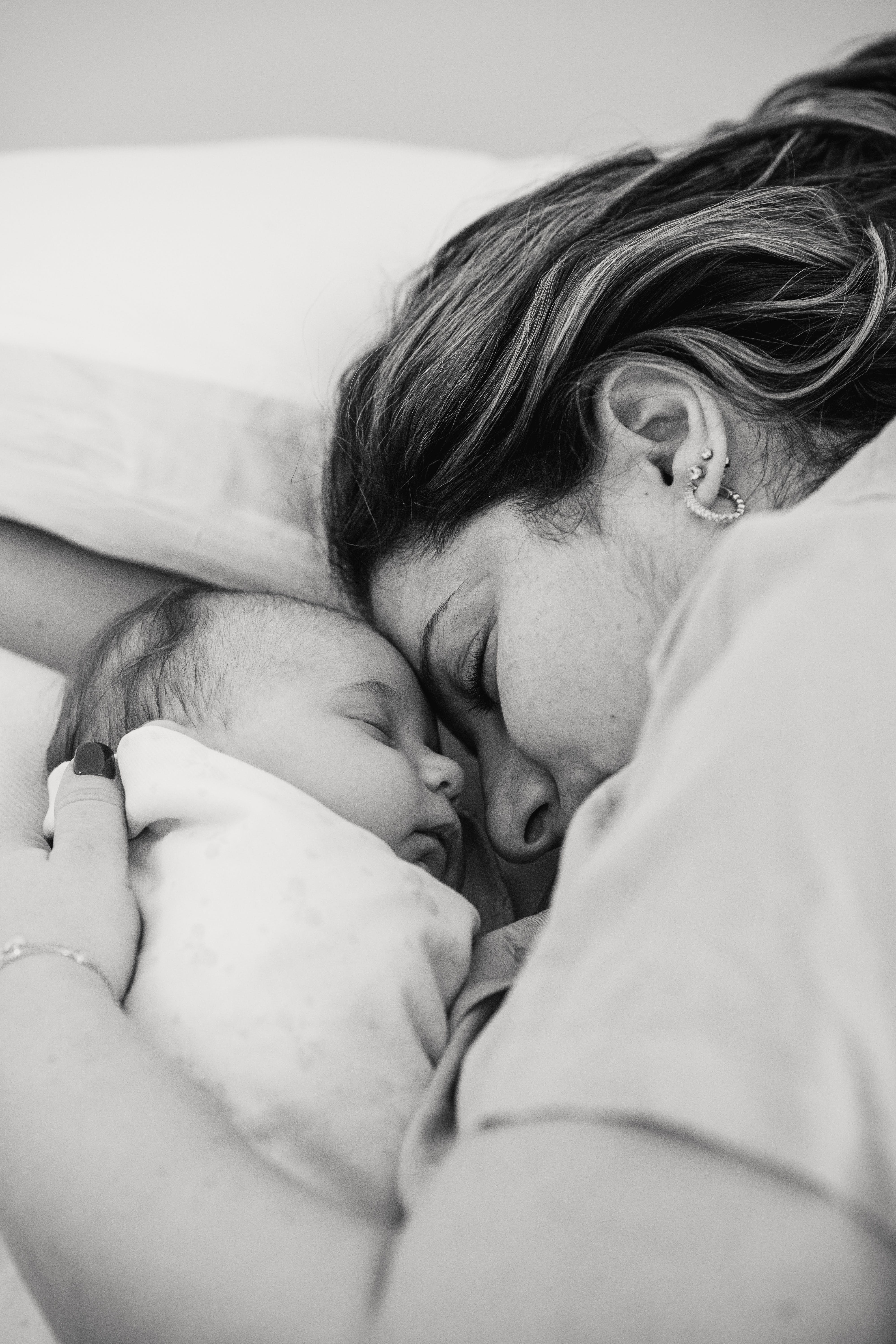 A mother lying down with her newborn baby | Source: Pexels