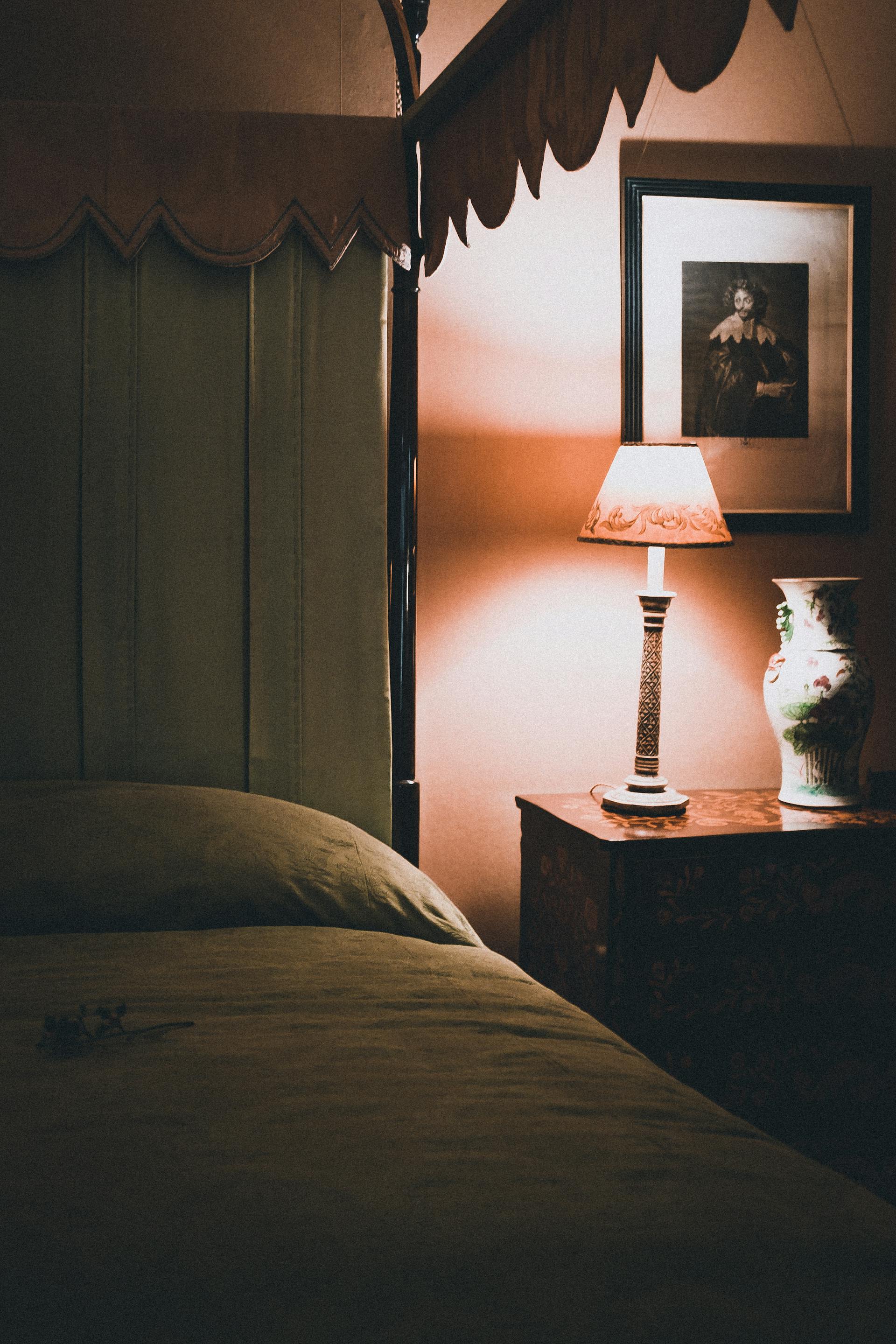 A close-up shot of a bedroom dimly lit with a table lamp | Source: Pexels