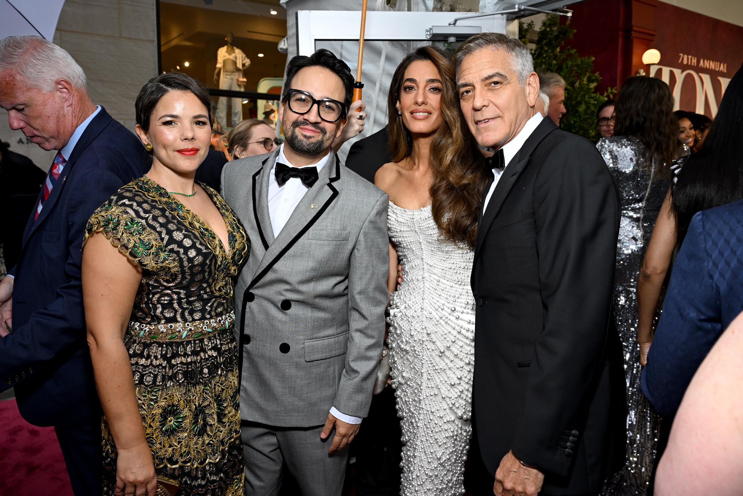 George and Amal Clooney join Lin-Manuel Miranda and Vanessa Nadal for a group photo at the Tony Awards. Amal’s pearl-covered gown adds a sparkle to the friendly moment, while George leans in with a composed half-smile.