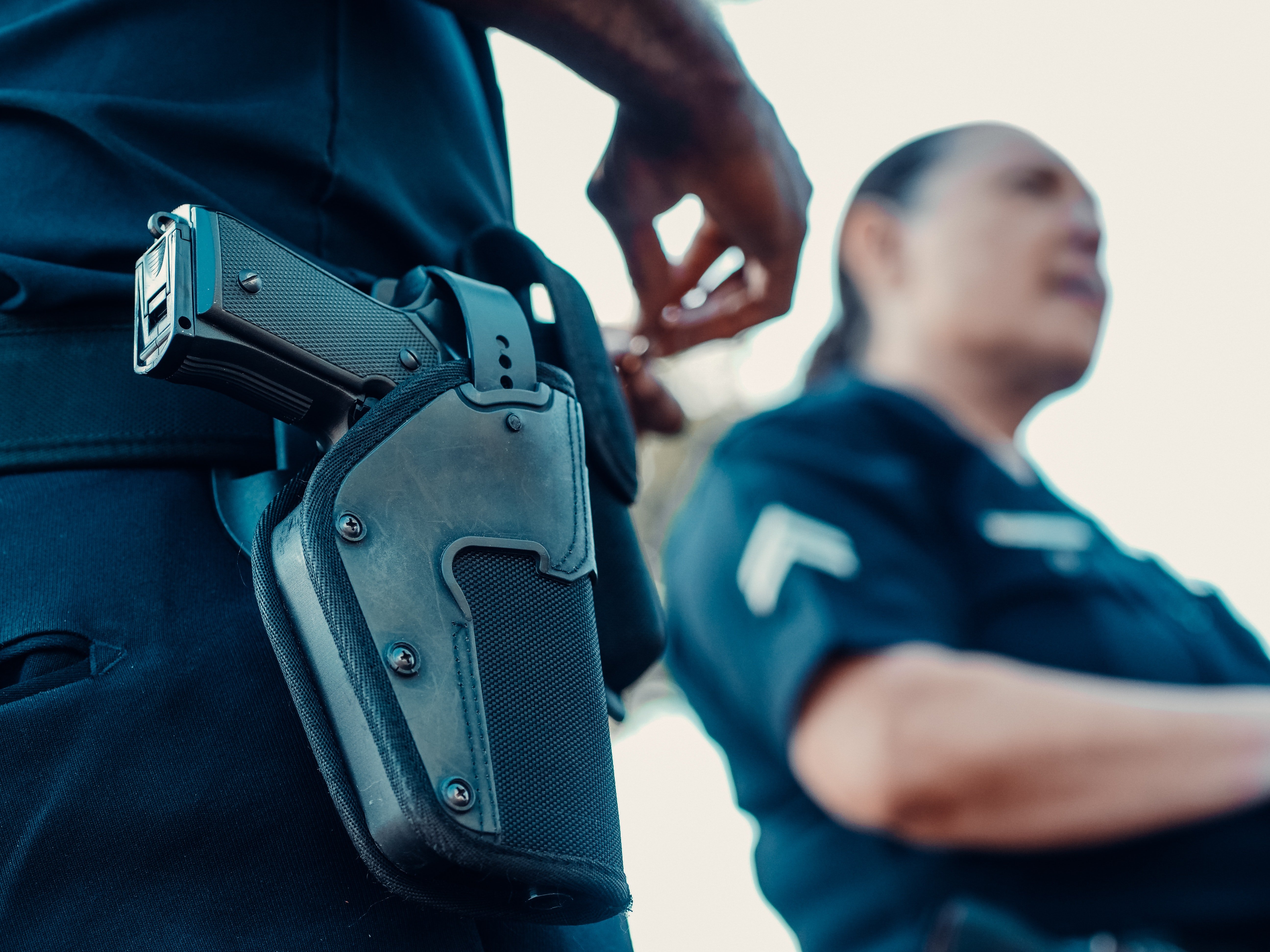 A weapon in the holster with a police women in the backgroung. | Pexels/ Kidel Media