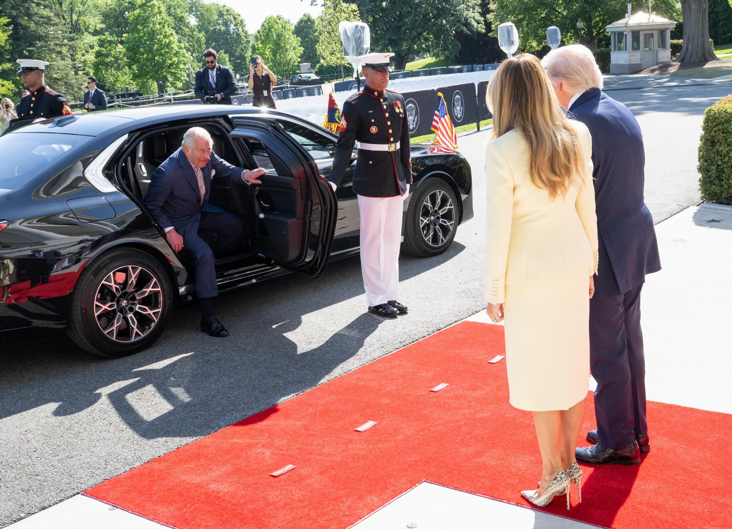 King Charles III was seen stepping out of a black presidential vehicle onto the White House's red-carpeted South Lawn as U.S. President Donald Trump and First Lady Melania Trump stood ready to receive him on 27 April 2026 in Washington, D.C. Flanked by a uniformed Marine and watched by photographers, the carefully staged arrival marked the formal start of the four-day state visit.