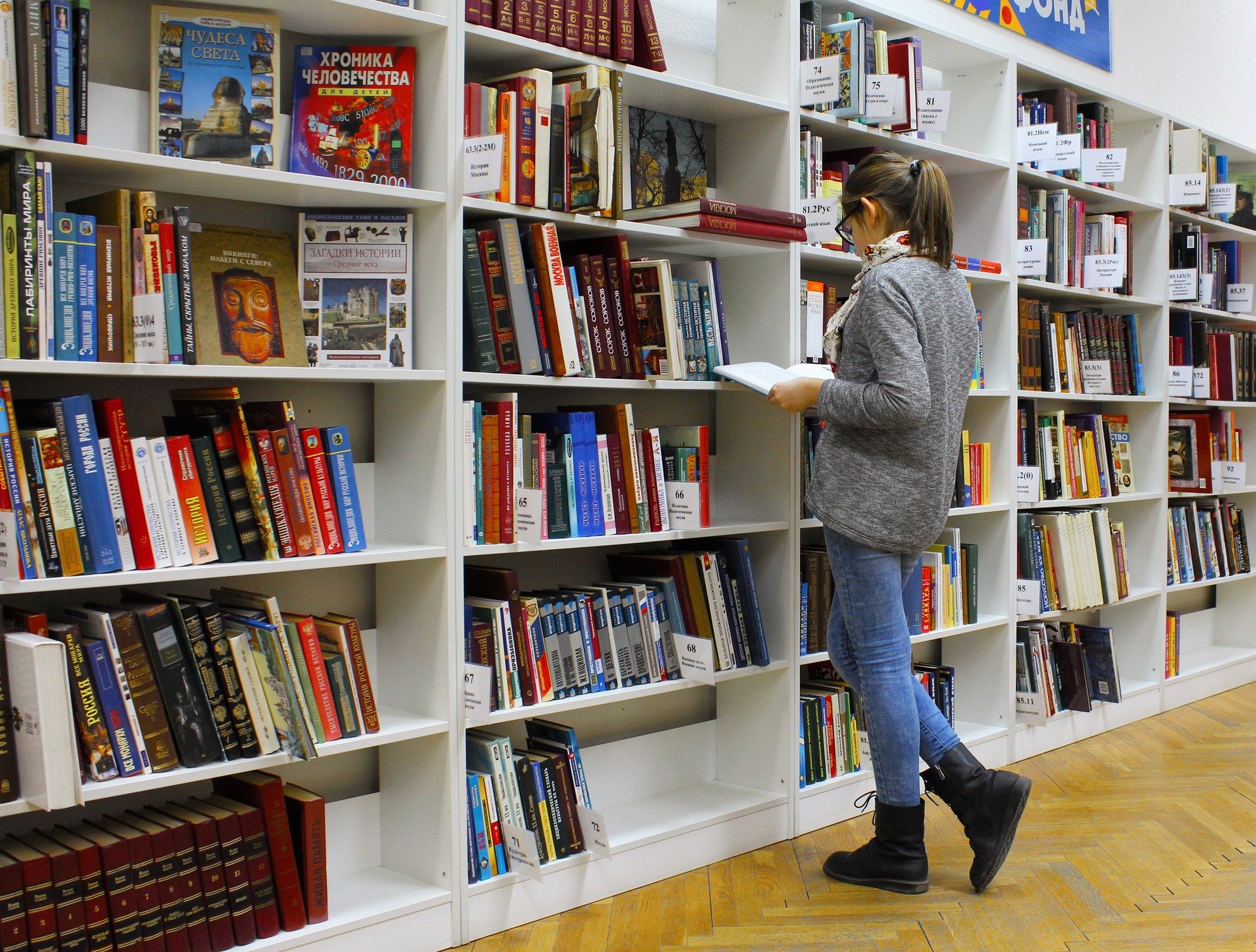 Junge Frau auf der Suche nach einem Buch zum Lesen in der Bibliothek. | Quelle: Pixabay