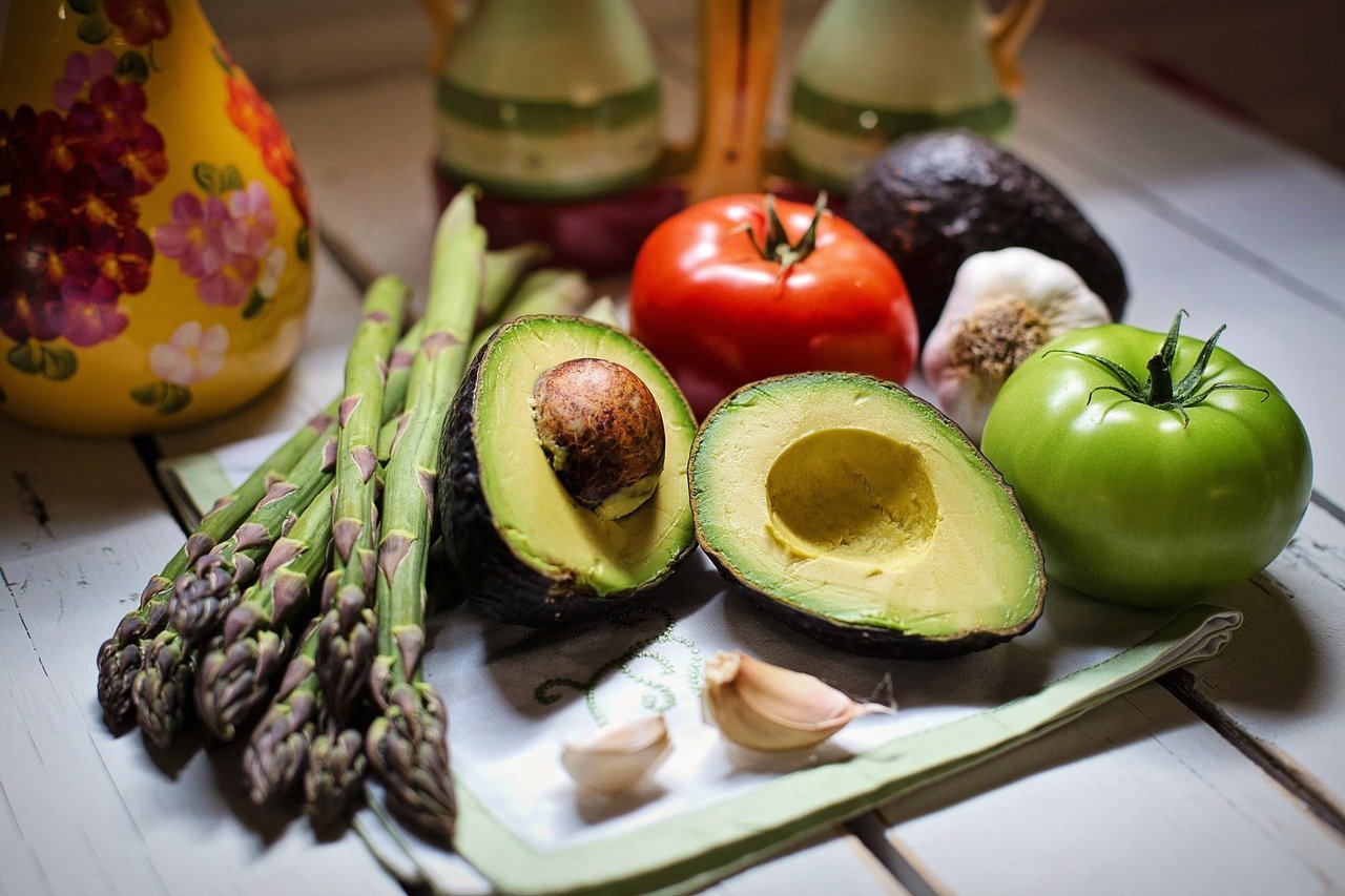 Asparraghus, avocado, tomato, and garlic on a kitchen table. | Image: Pixabay.