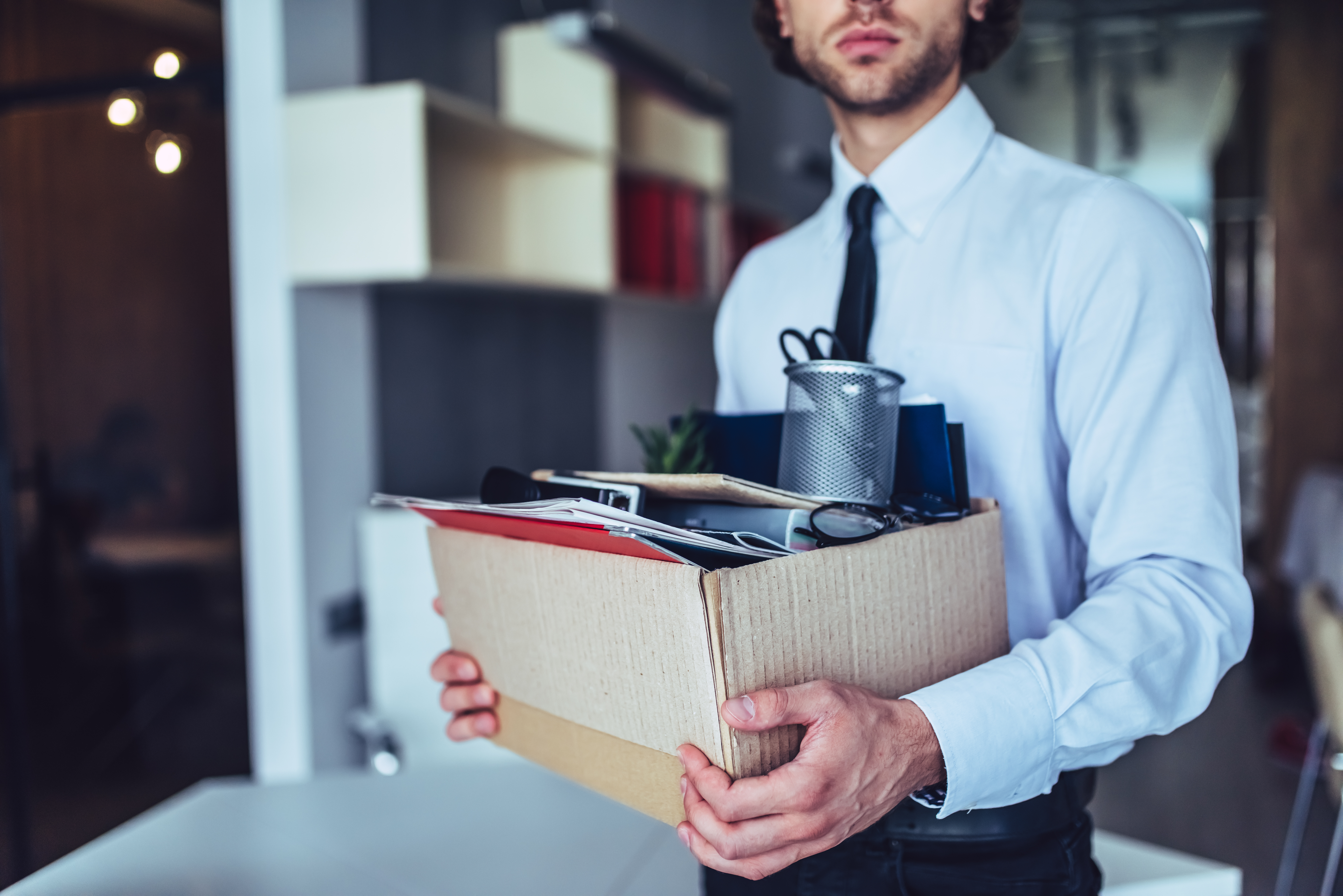A man holding a carton full of his belongings inside an office | Source: Shutterstock