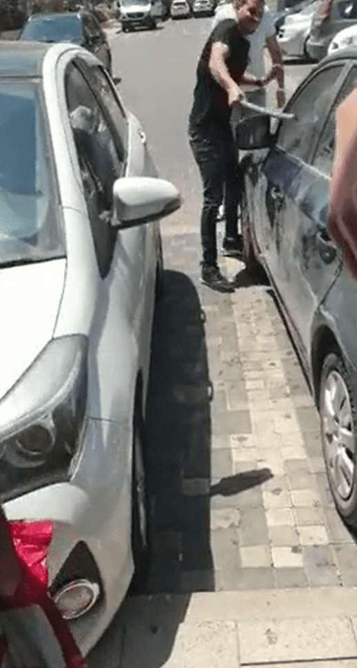 Man hitting the front of a car window with a steel pole. │Source: Reddit/u/hardisc