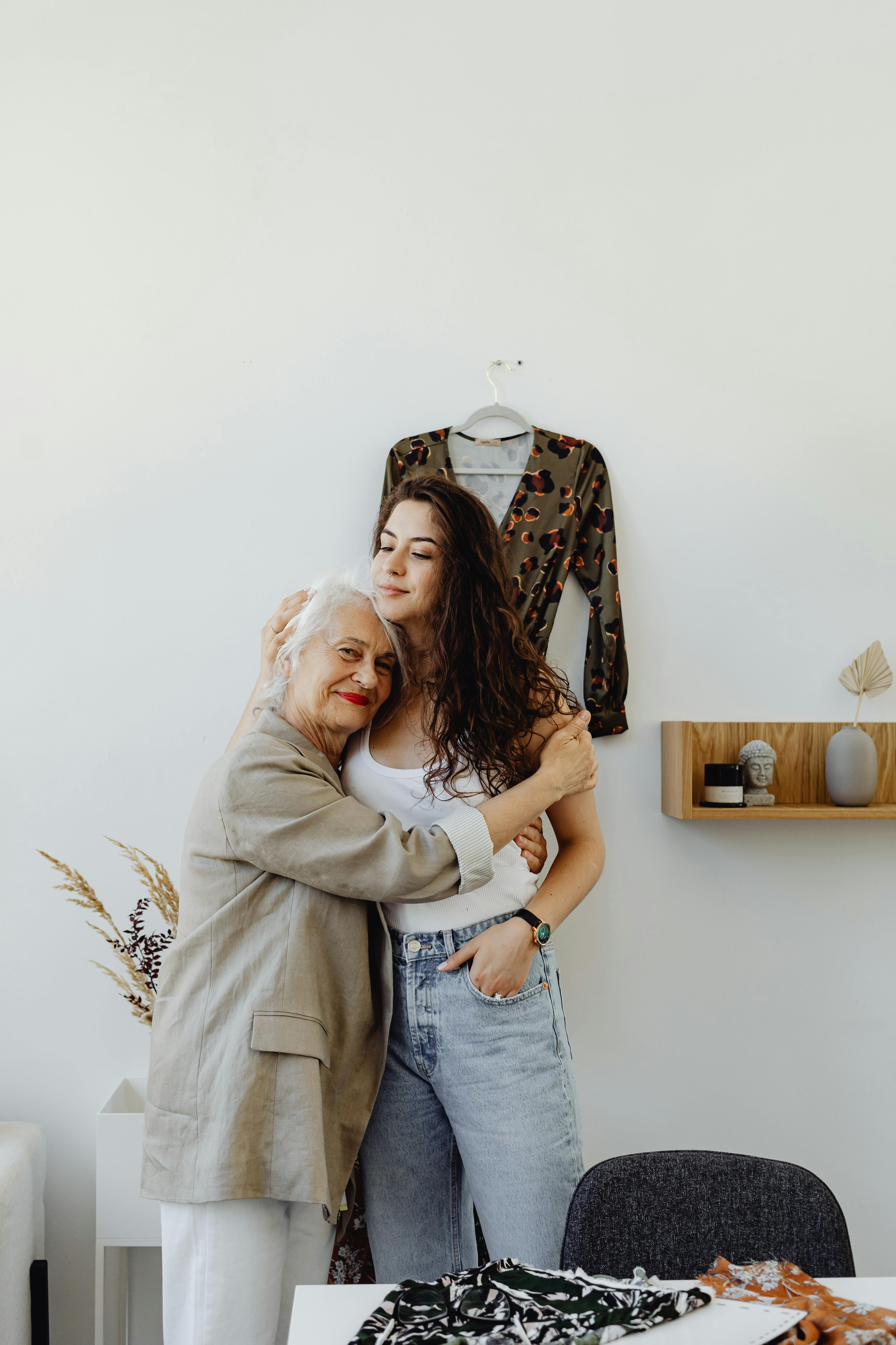 An upset-looking younger woman hugging an older one | Source: Pexels