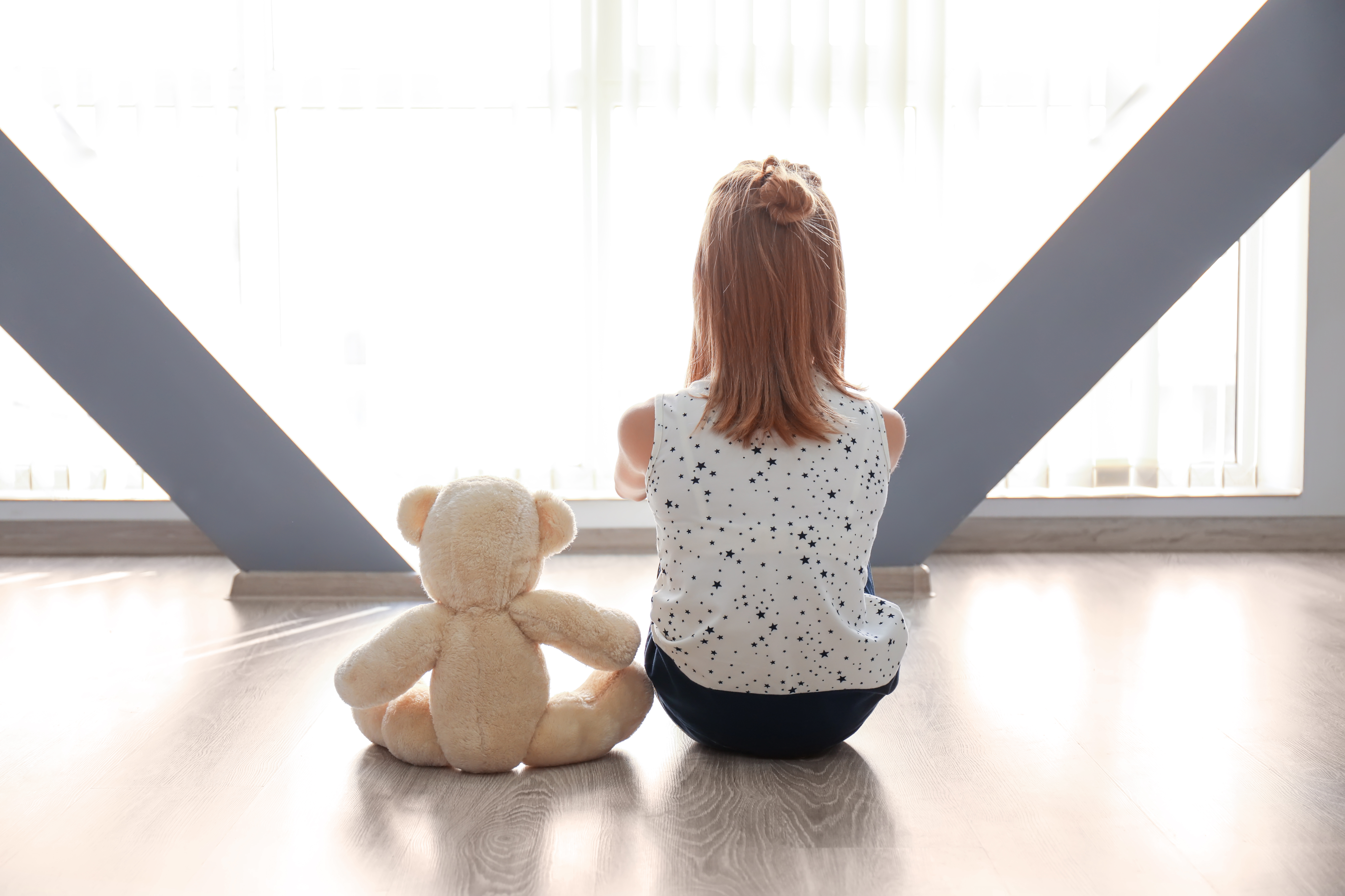 A little girl sitting on the floor with her teddy bear | Source: Shutterstock