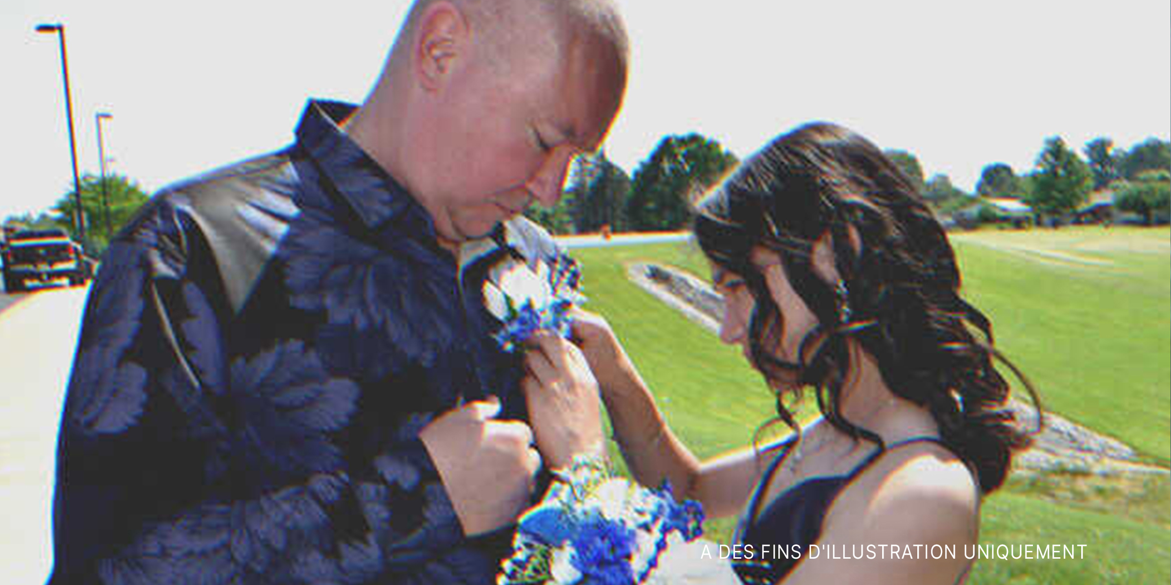 Une jeune fille épinglant des fleurs sur la chemise d'un homme plus âgé | Source : Shutterstock
