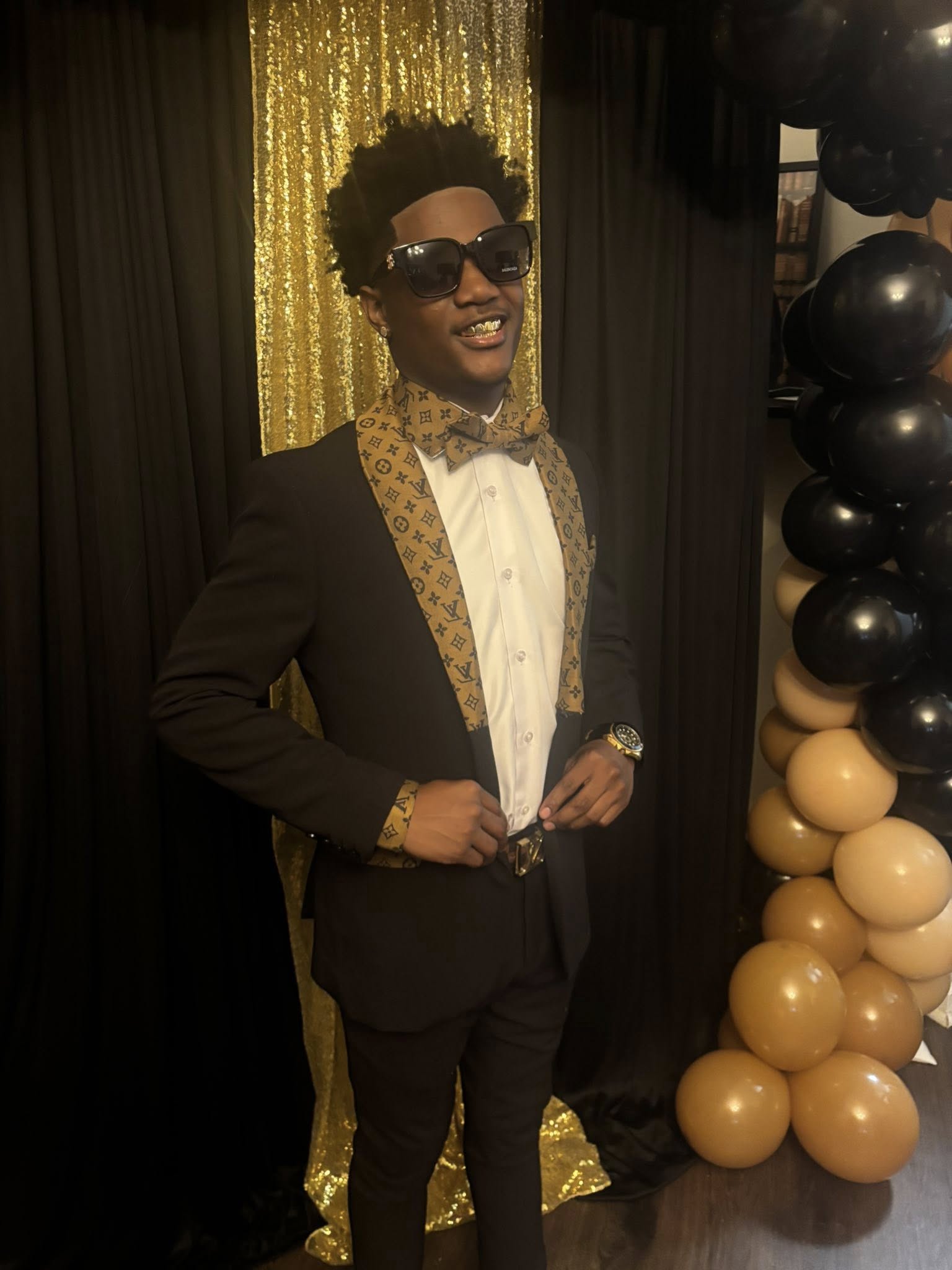 Ladainian Cathey smiling for the camera as he adjusts his suit. | Source: Facebook/Lakeisha Johnson