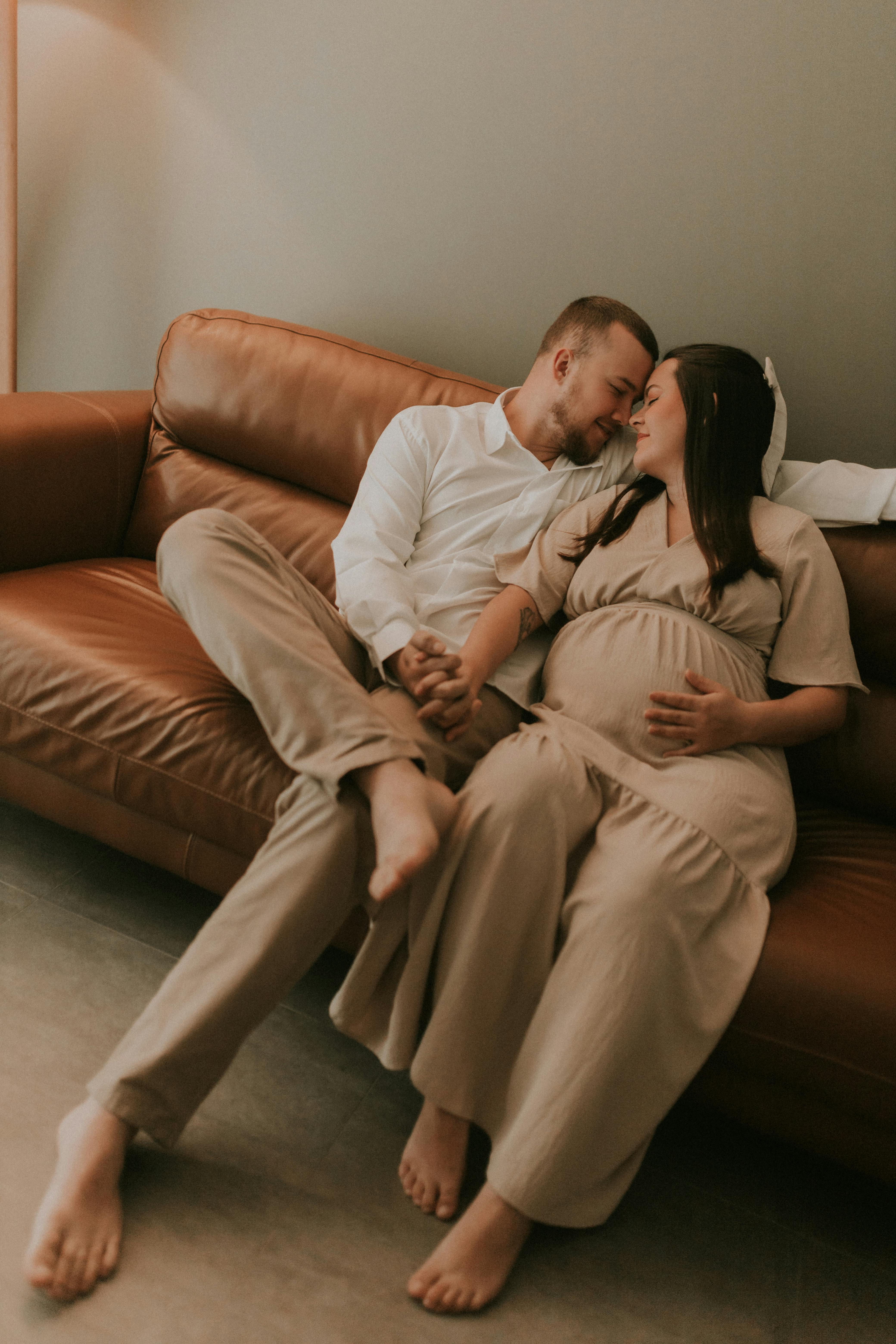 A pregnant woman and her husband on a sofa | Source: Pexels