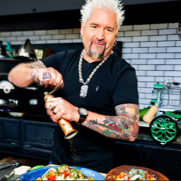 Guy Fieri cooking and posing for a picture, posted on May 14, 2024 | Source: Instagram/menshealthmag and guyfieri