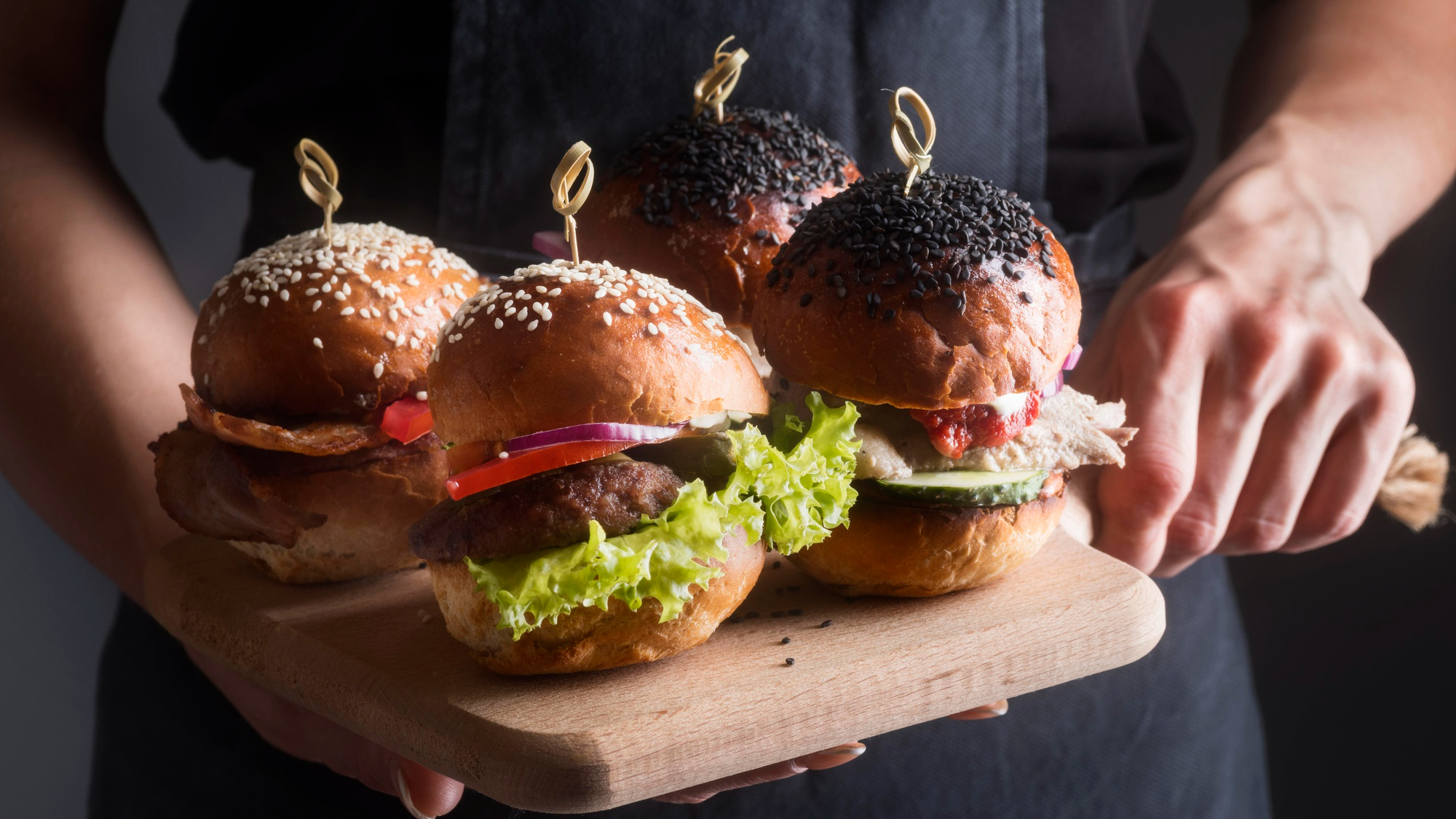 A waiter holding four burgers on a serving board | Source: Freepik