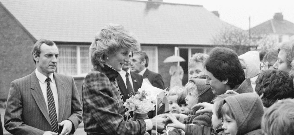 Der Prinz und die Prinzessin von Wales besuchen Mid Glamorgan in Wales, hinter Prinzessin Diana steht Leibwächter Barry Mannakee, der am 29. Januar 1985 eine diagonal gestreifte Krawatte und einen Mantel/Mac trägt | Quelle: Getty Images