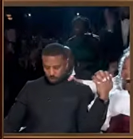 Michael B. Jordan sits in his seat with a focused, almost stunned expression as the moment unfolds around him. | Source: YouTube/ABCNews