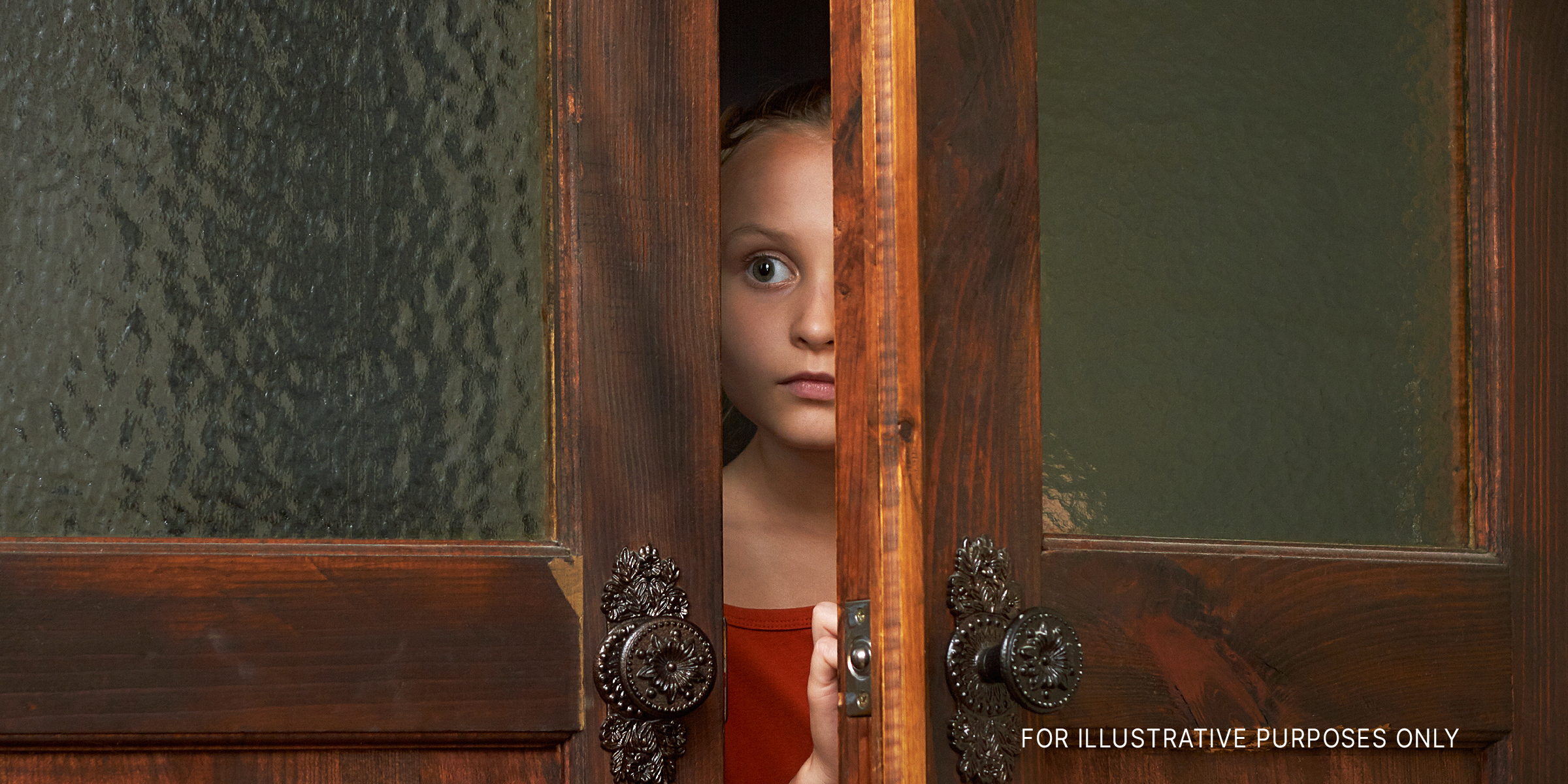 A little scared girl looking through the door slit | Source: Shutterstock