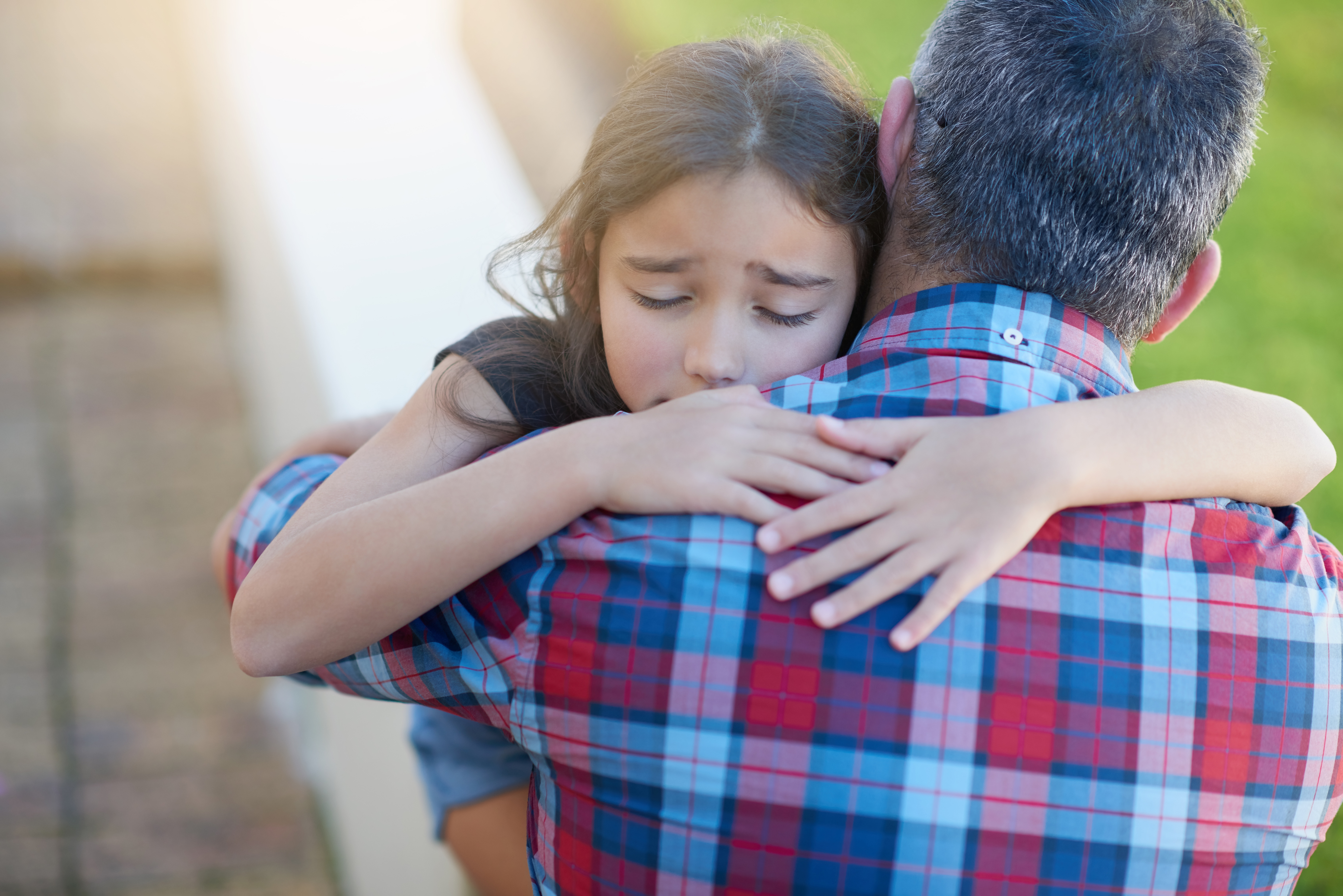 A father hugs his sad, young daughter to comfort her amid her heartache | Source: Shutterstock
