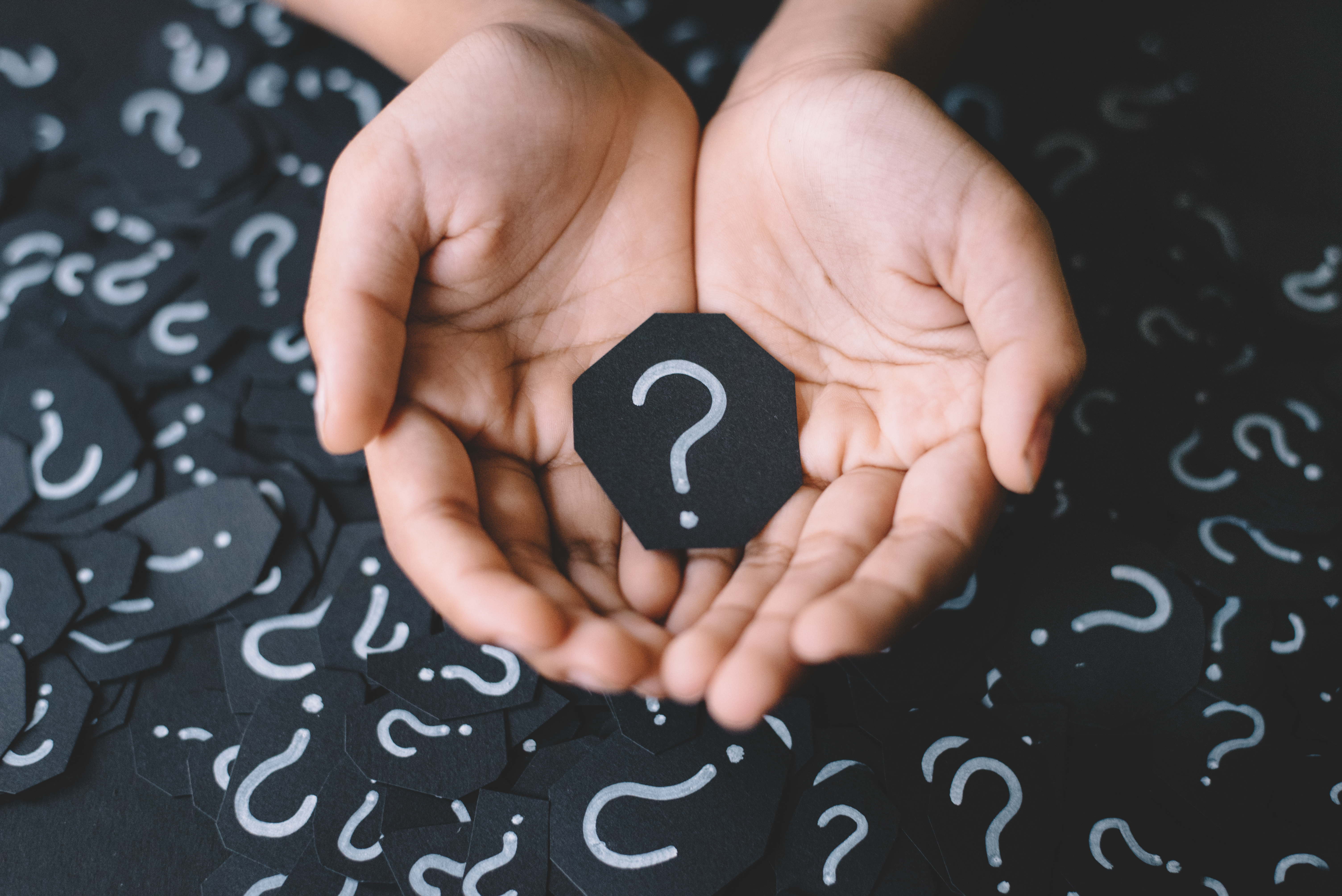 Two hands holding a paper cut-out of the question mark sign | Source: Shutterstock