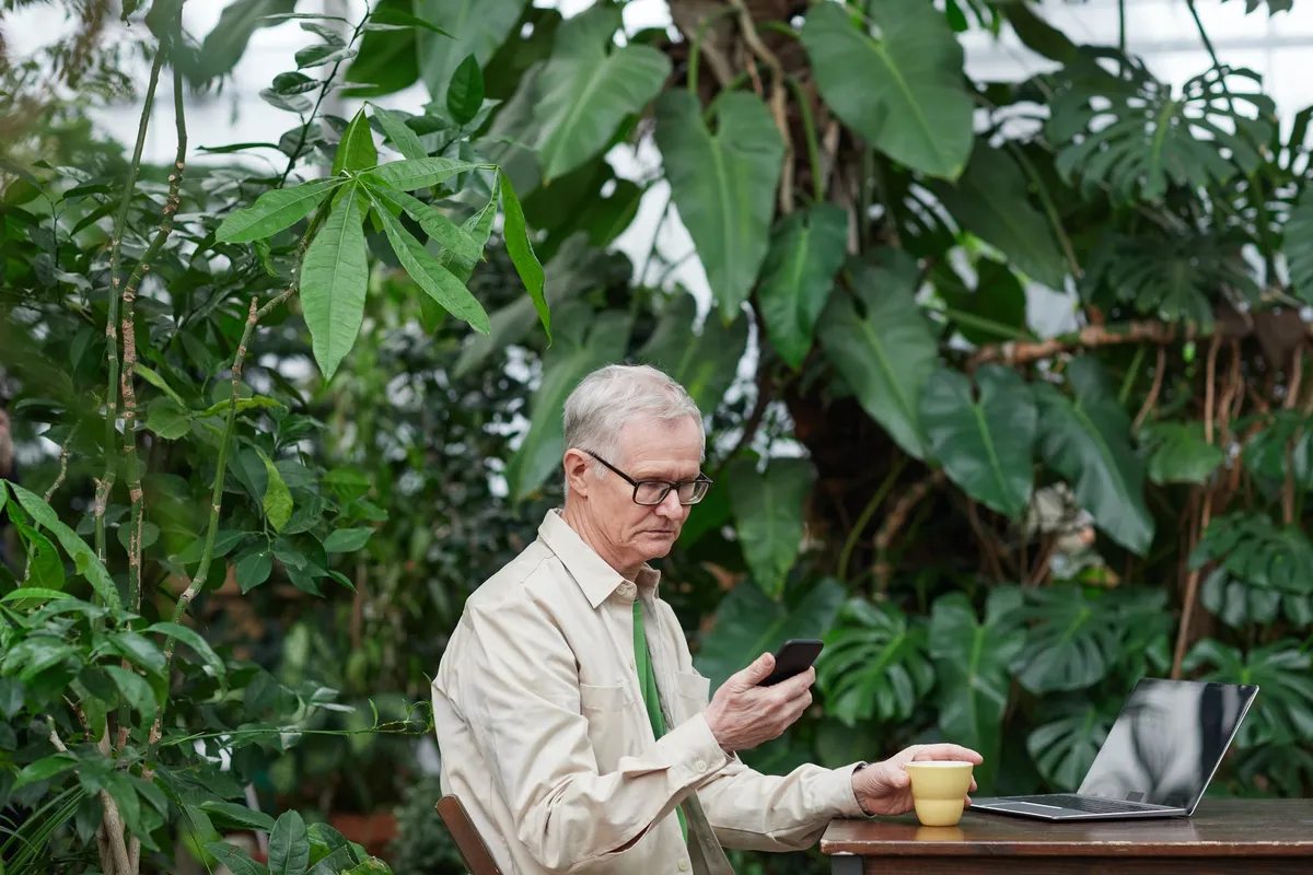 Un homme assis à l'extérieur regardant son téléphone portable | Source : Pexels