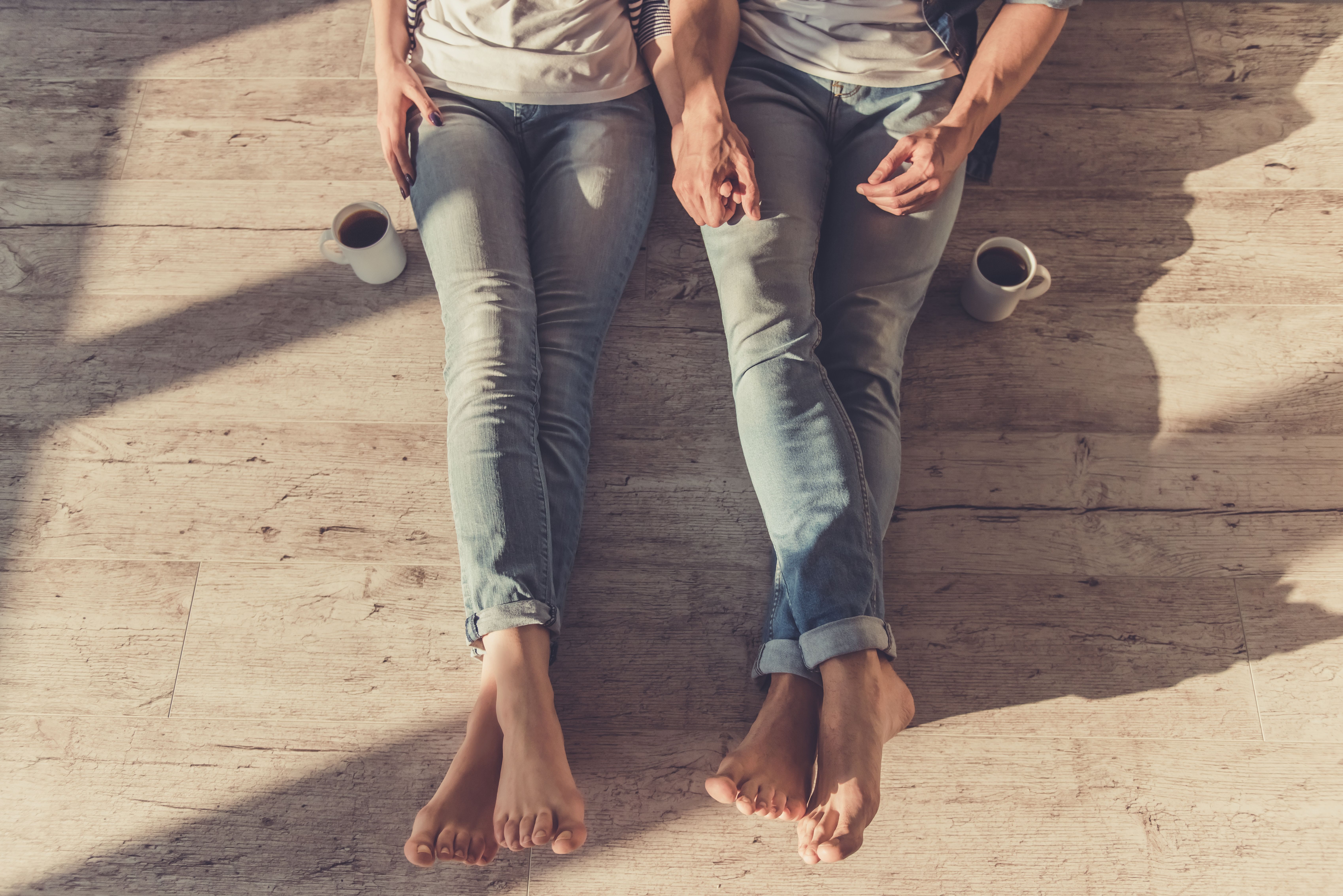 Bild eines schönen jungen Ehepaares, das beim Sitzen auf dem Boden Hände hält. | Foto von: VGstockstudio via Shutterstock