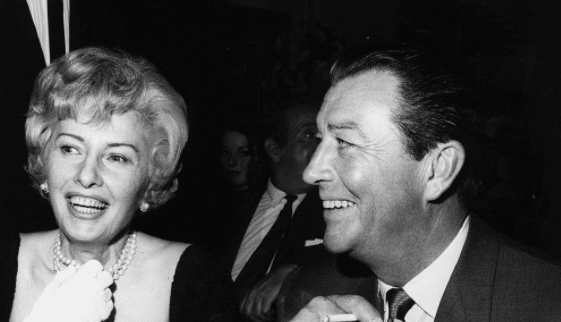 American film stars Barbara Stanwyck and Robert Taylor who were married in 1939 and divorced in 1951 at a press party to mark the start of production of their new film 'The Night Walker'. May 1964. | Source: Getty Images