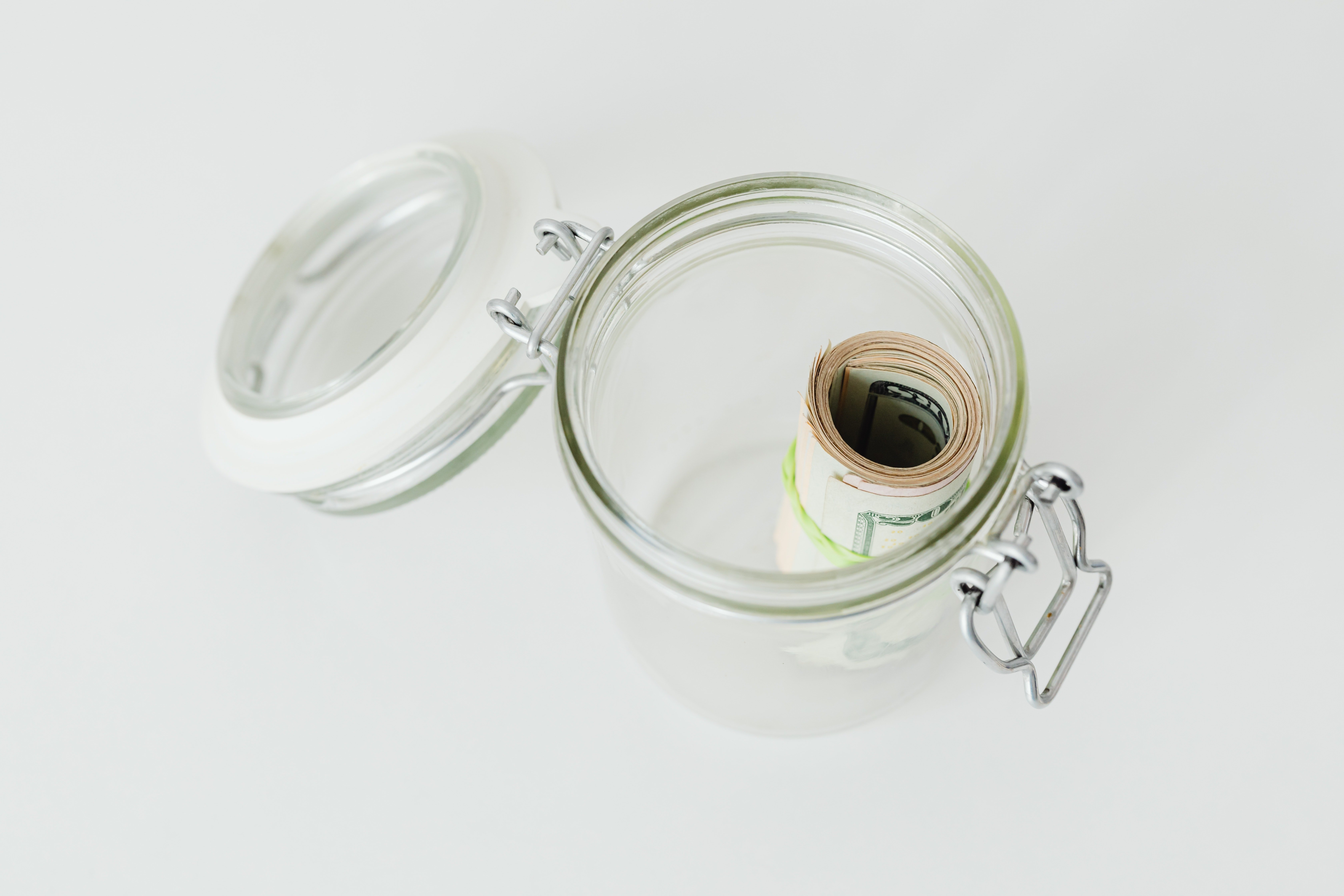 Un recipiente de vidrio con un rollo de billetes en su interior. | Foto: Pexels
