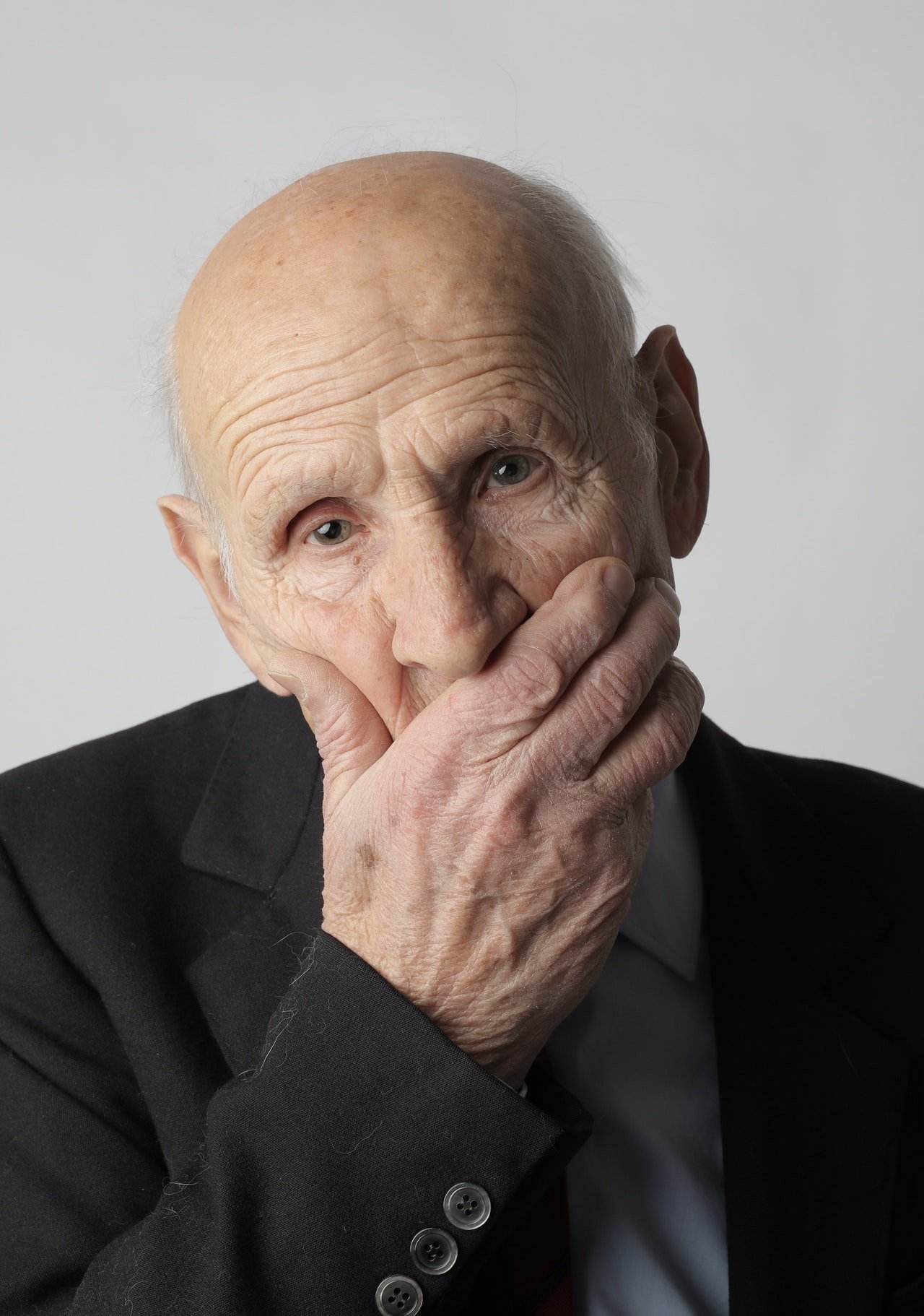 Anciano con la mano en la boca. | Foto: Pexels