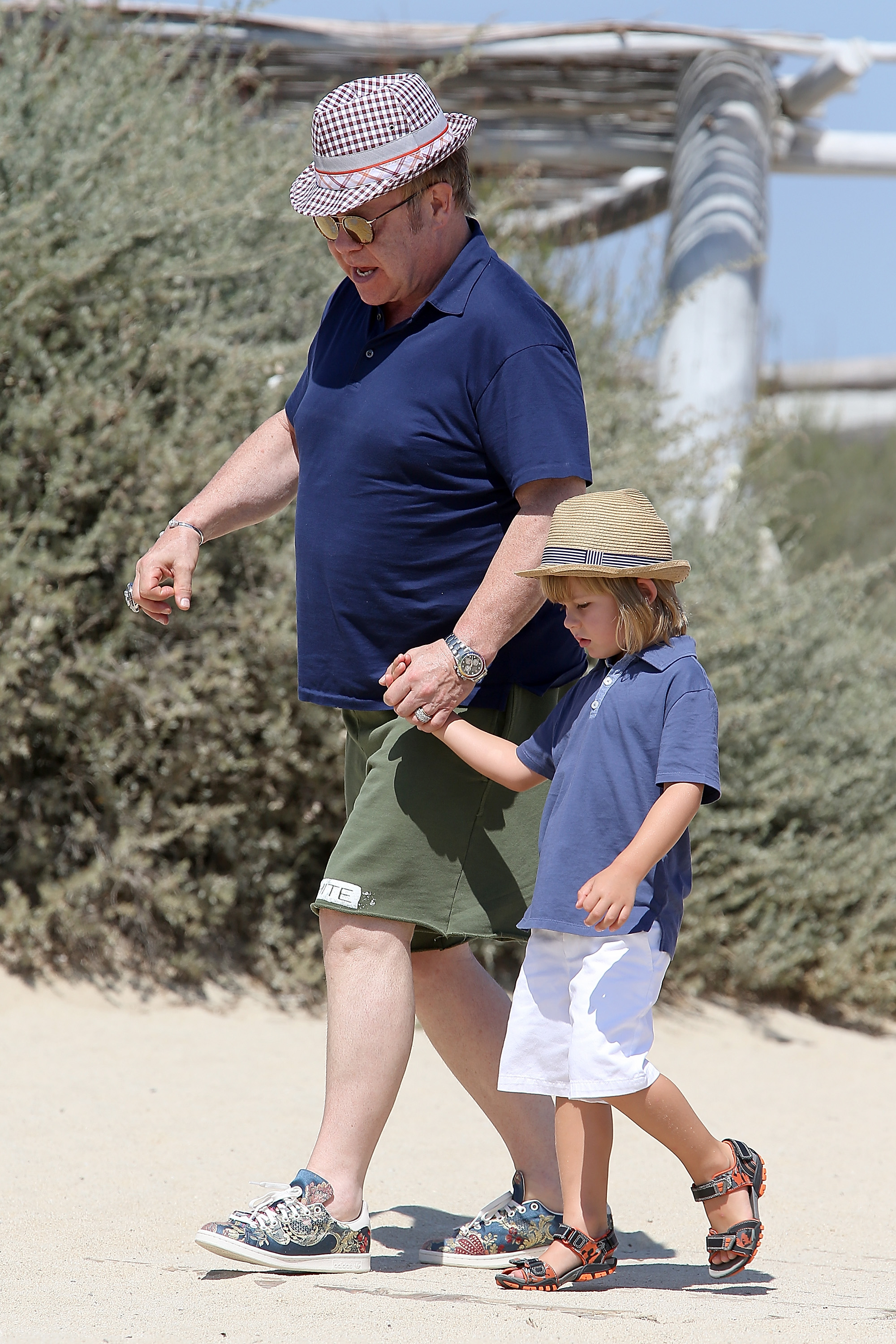 Sir Elton John kept a firm but gentle hold on Zachary John Furnish-John's hand as they strolled through Saint-Tropez, France, on August 21, 2015. Shielded from the summer sun in coordinating hats, the pair appeared relaxed and in step, with John dressed casually in a navy polo and green shorts while Zachary mirrored the laid-back mood in a blue shirt and white shorts.