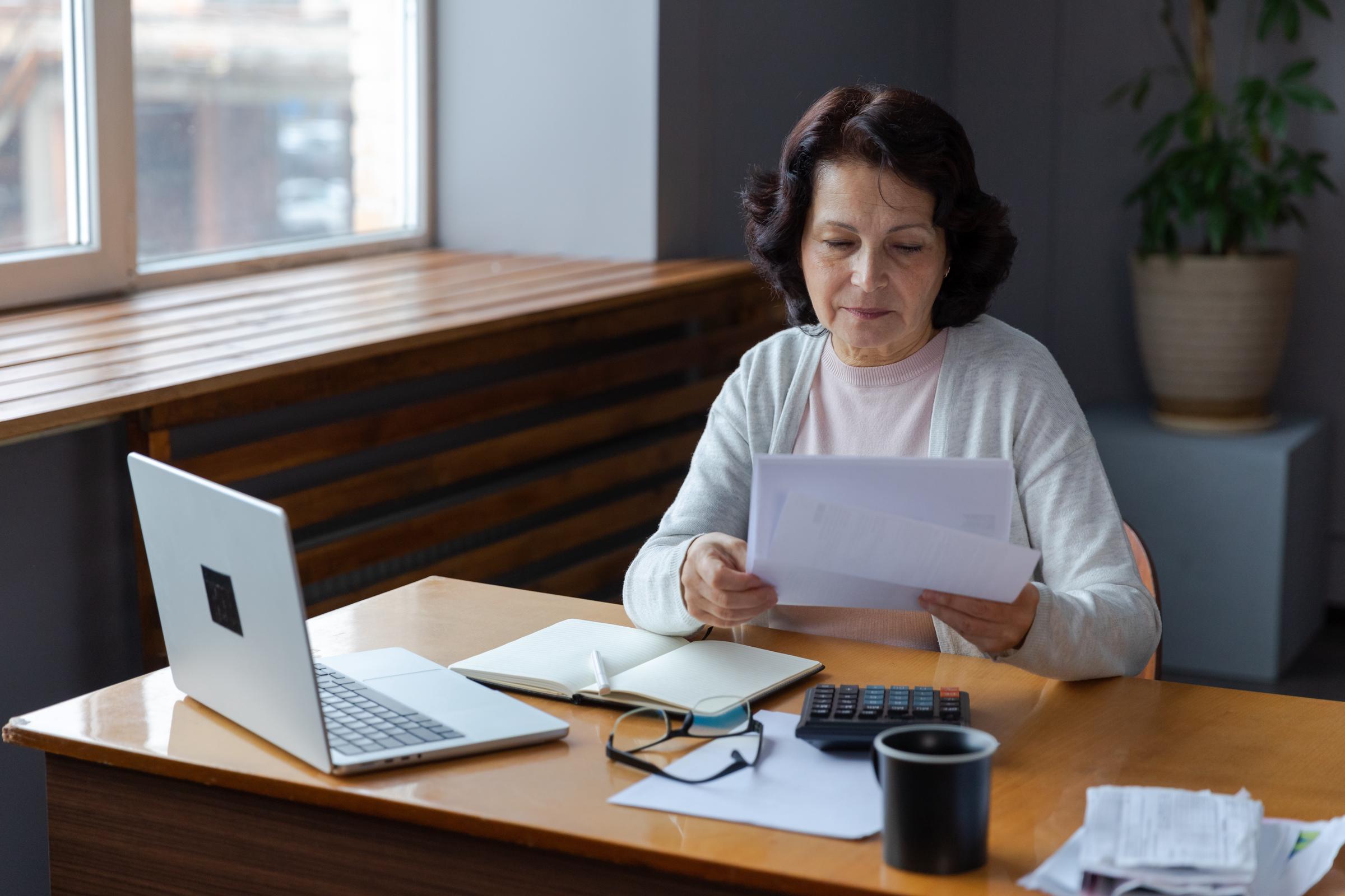 Woman reading documents on her office desk | Source: Shutterstock