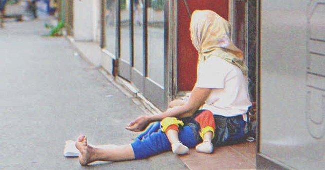 Una mendiga sentada en la calle con una bebé en brazos. | Foto: Shutterstock
