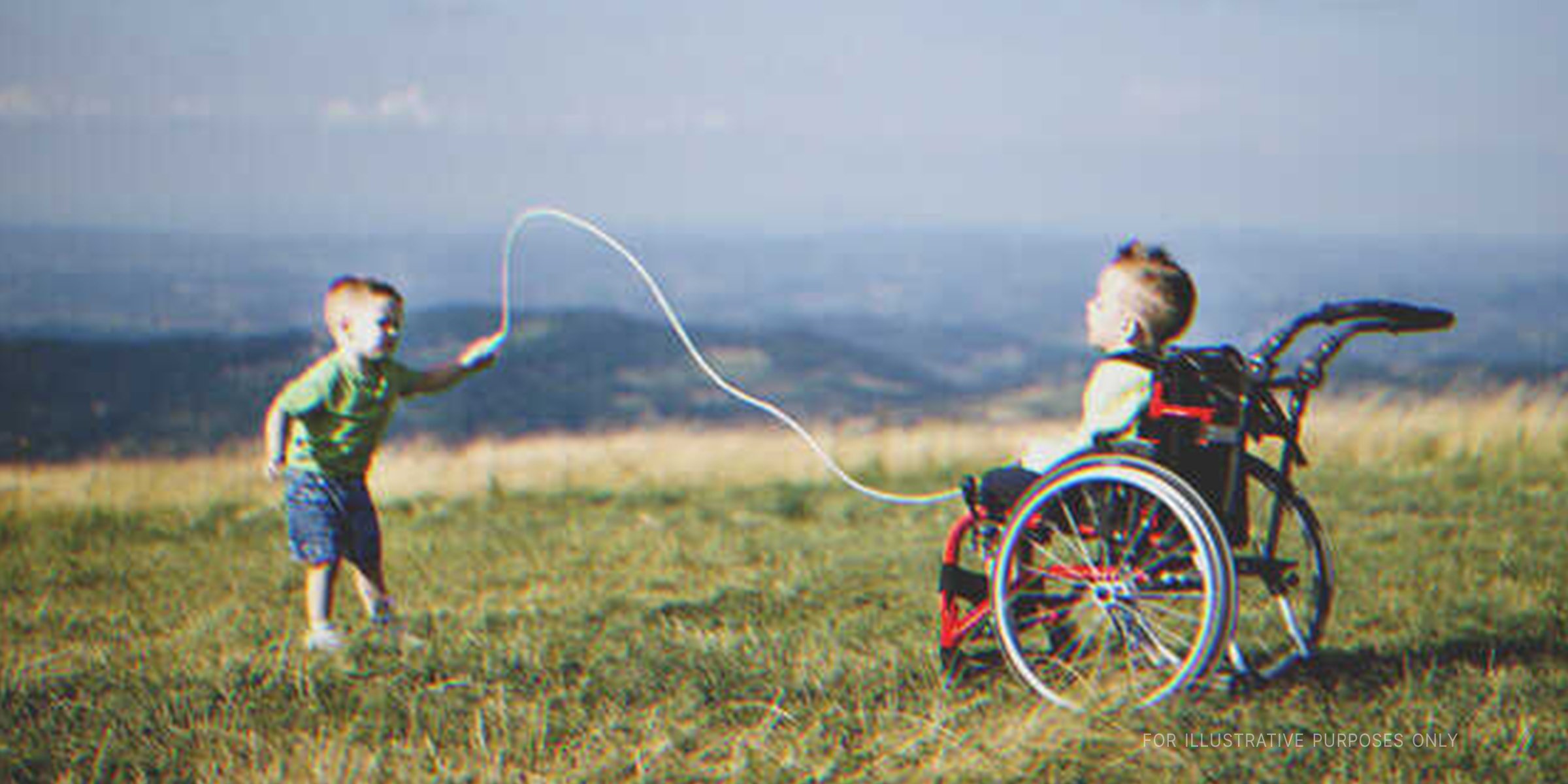 Boy playing with his wheelchair-borne twin on a meadow | Source: Getty Images