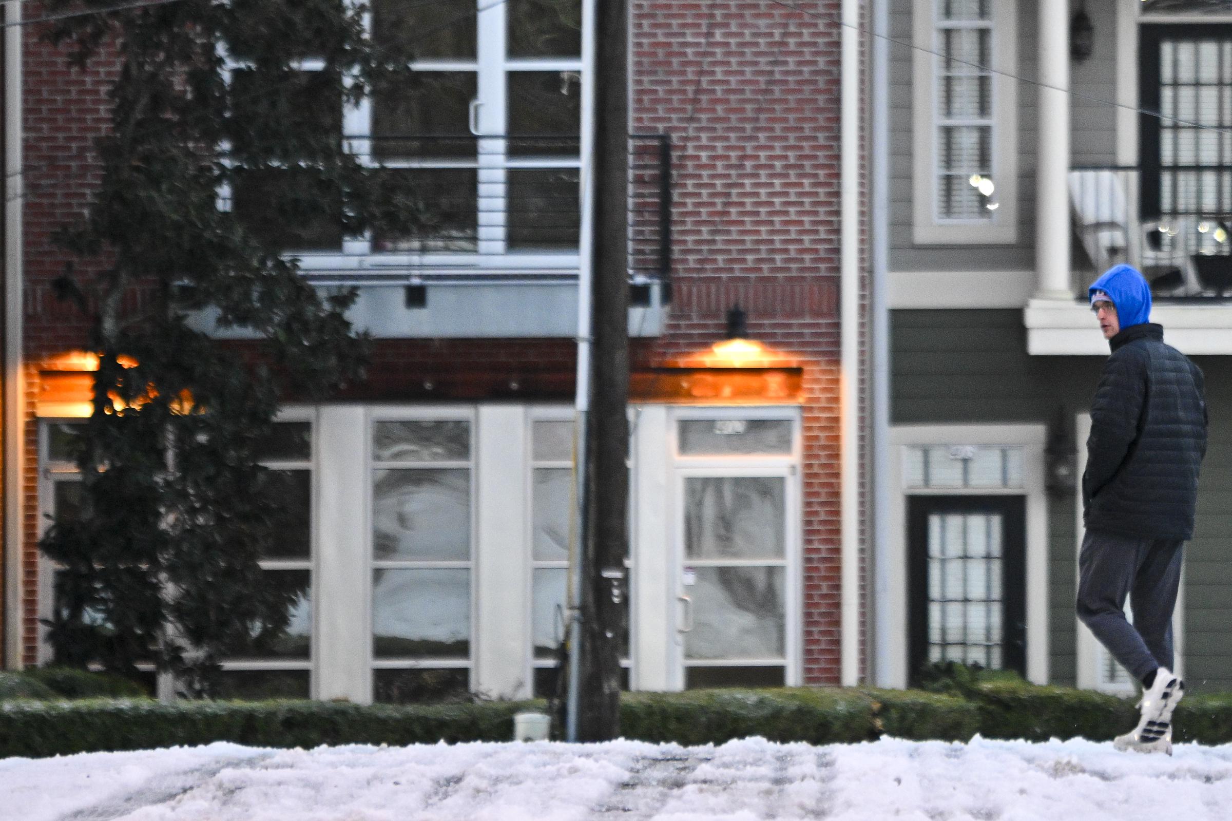 A resident walking in front of a house covered in snow. | Source: Getty Images