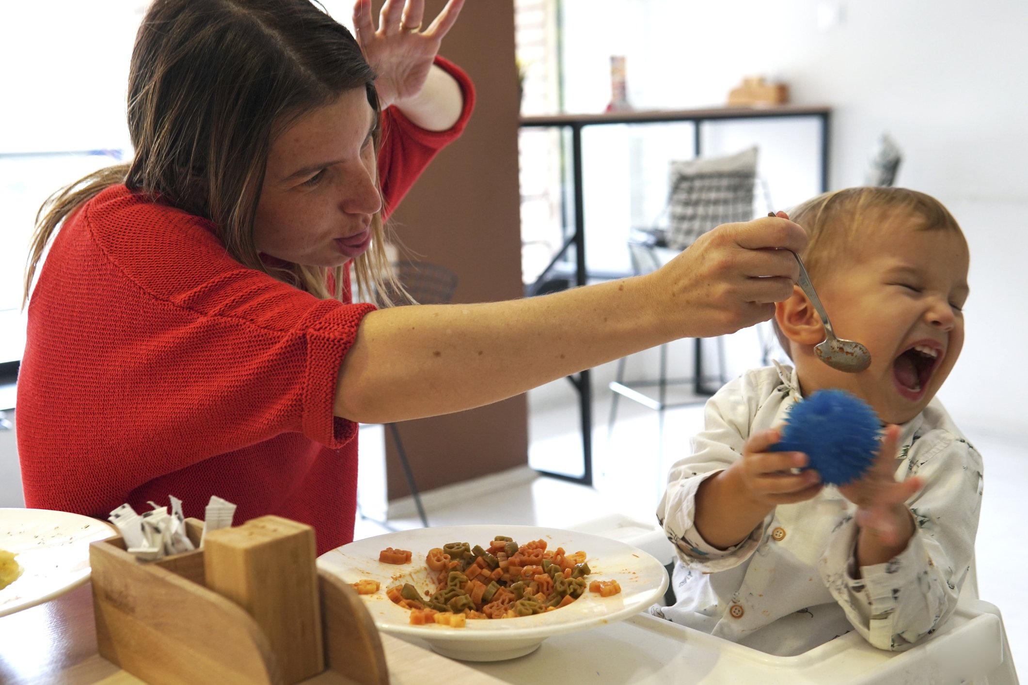 Un enfant pleure et refuse de manger dans un restaurant alors que sa mère tente de le nourrir | Photo : Getty Images