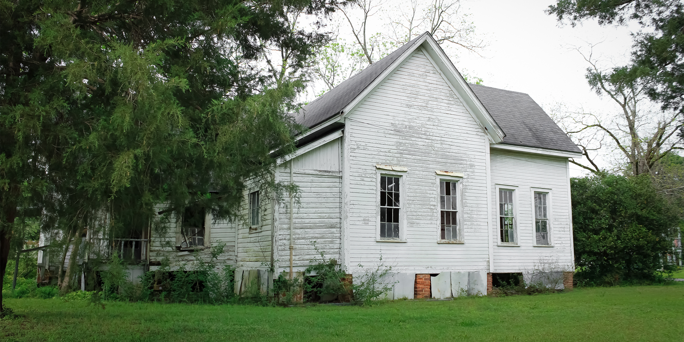 An old house surrounded by trees and a lush green lawn | Source: Shutterstock