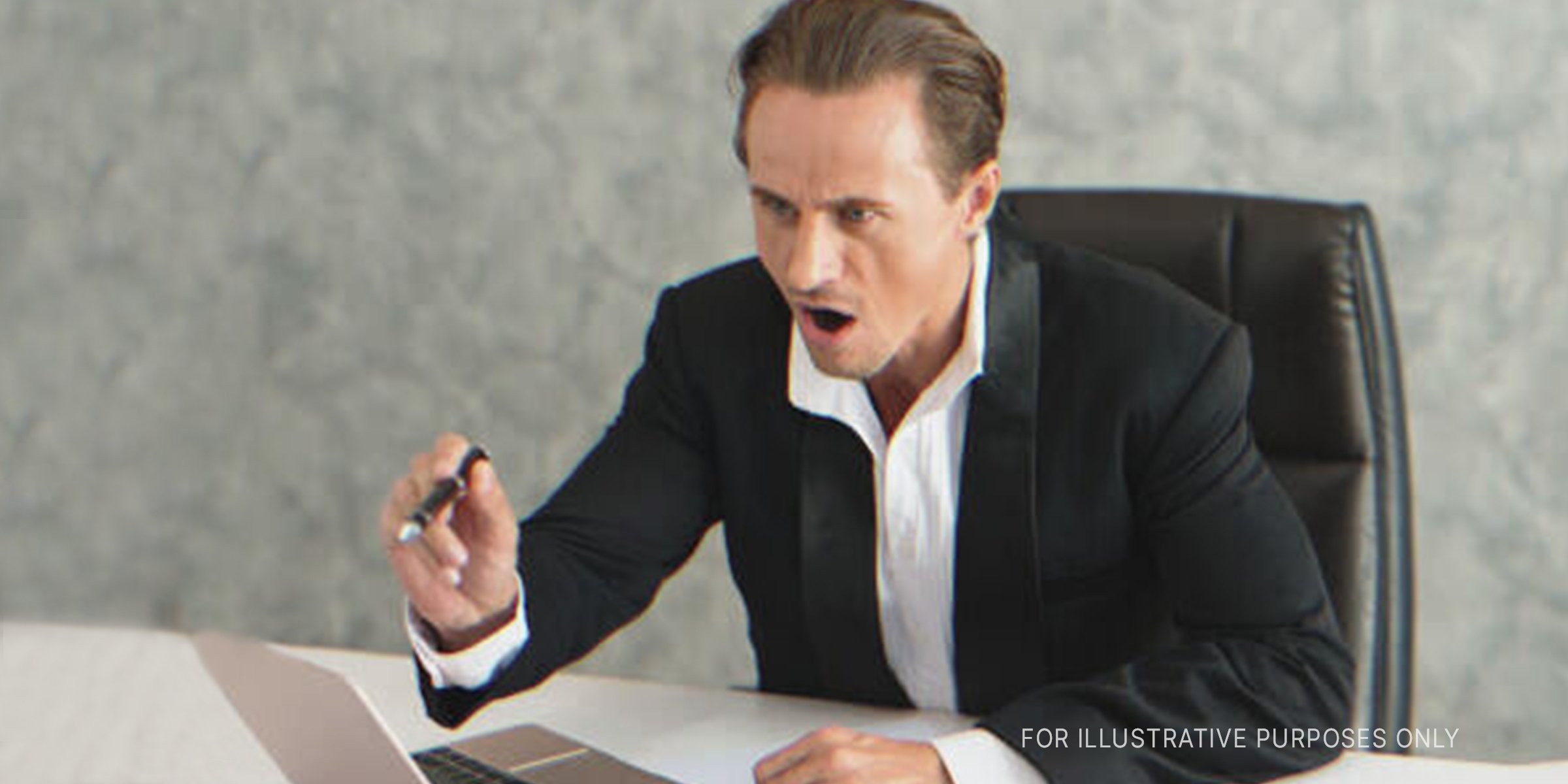 Man sitting on a desk, pointing angrily. | Source: Shutterstock