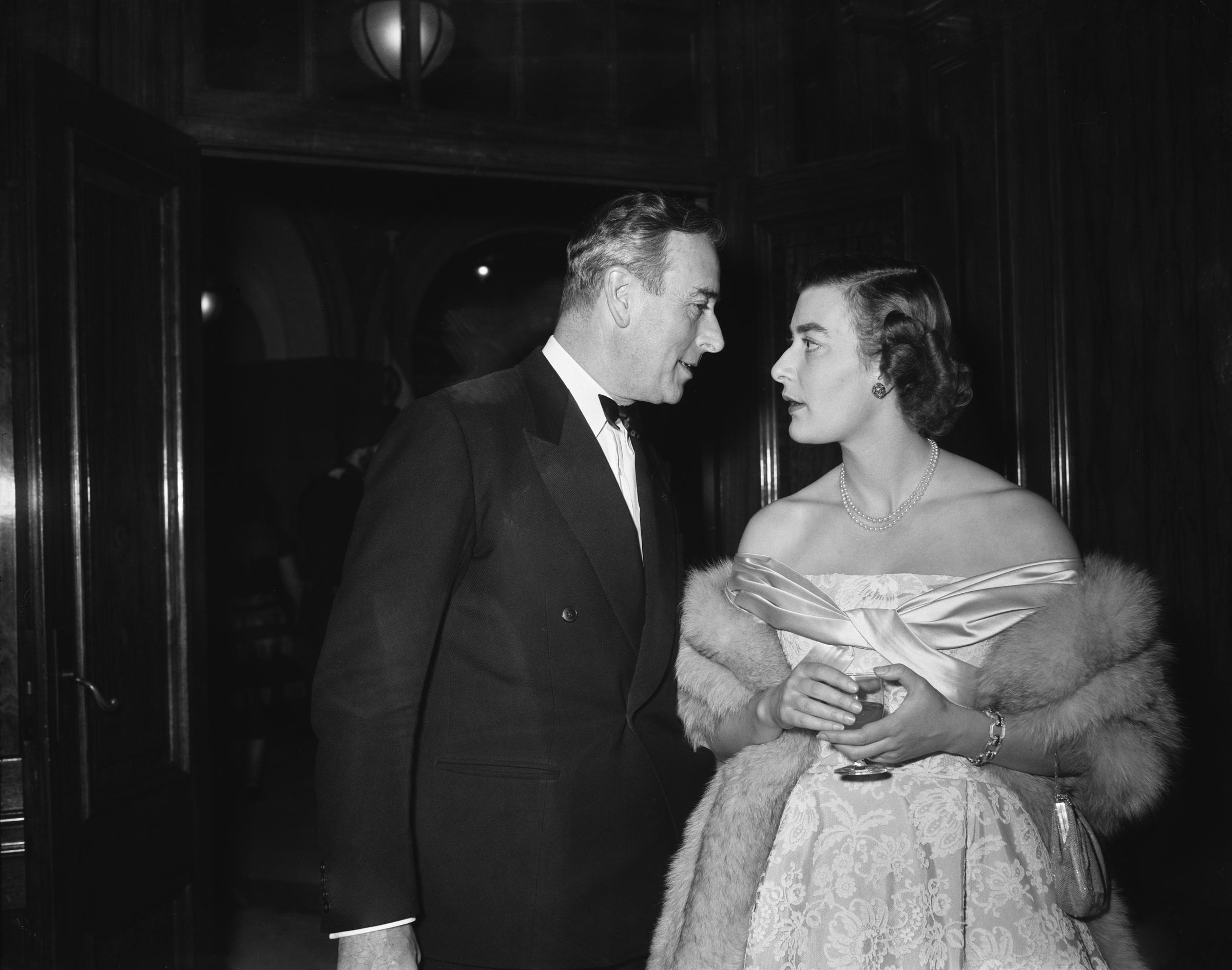 Taken on 31 January 1956 in the United Kingdom, Lady Pamela Mountbatten is pictured in an off-shoulder evening gown and fur wrap beside her father, Lord Louis Mountbatten, as the pair share a poised yet intimate exchange during a formal evening engagement.