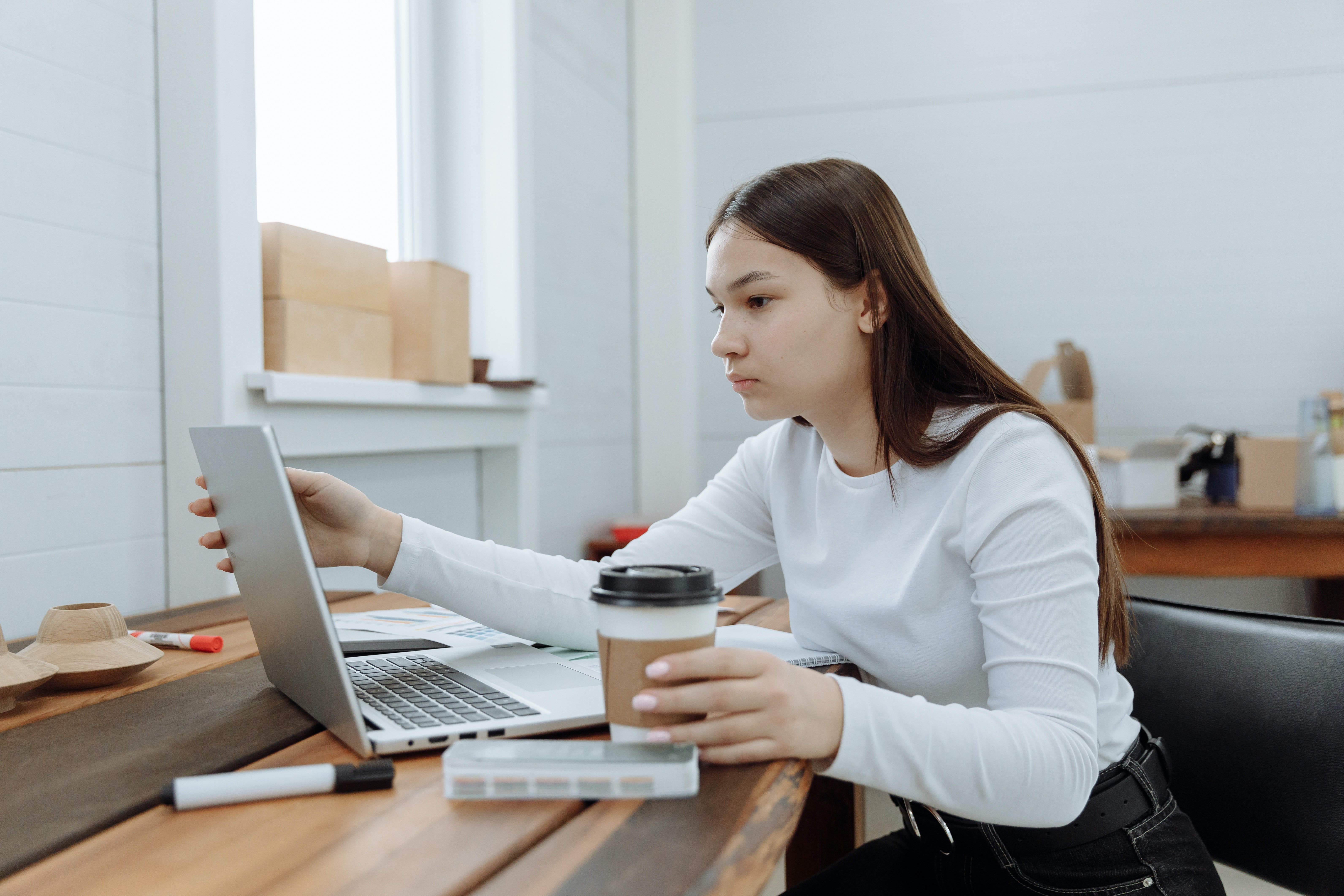 A woman staring at her computer screen with coffee in hand. | Photo: Pexels