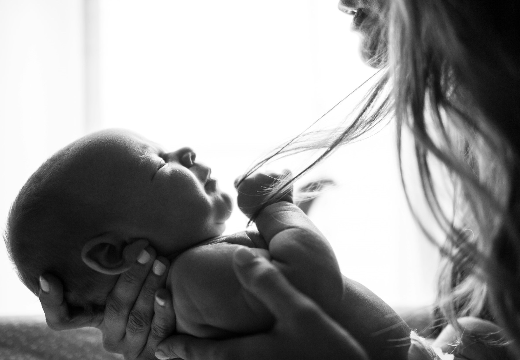 Grayscale image of a woman carrying a newborn baby | Source: Unsplash