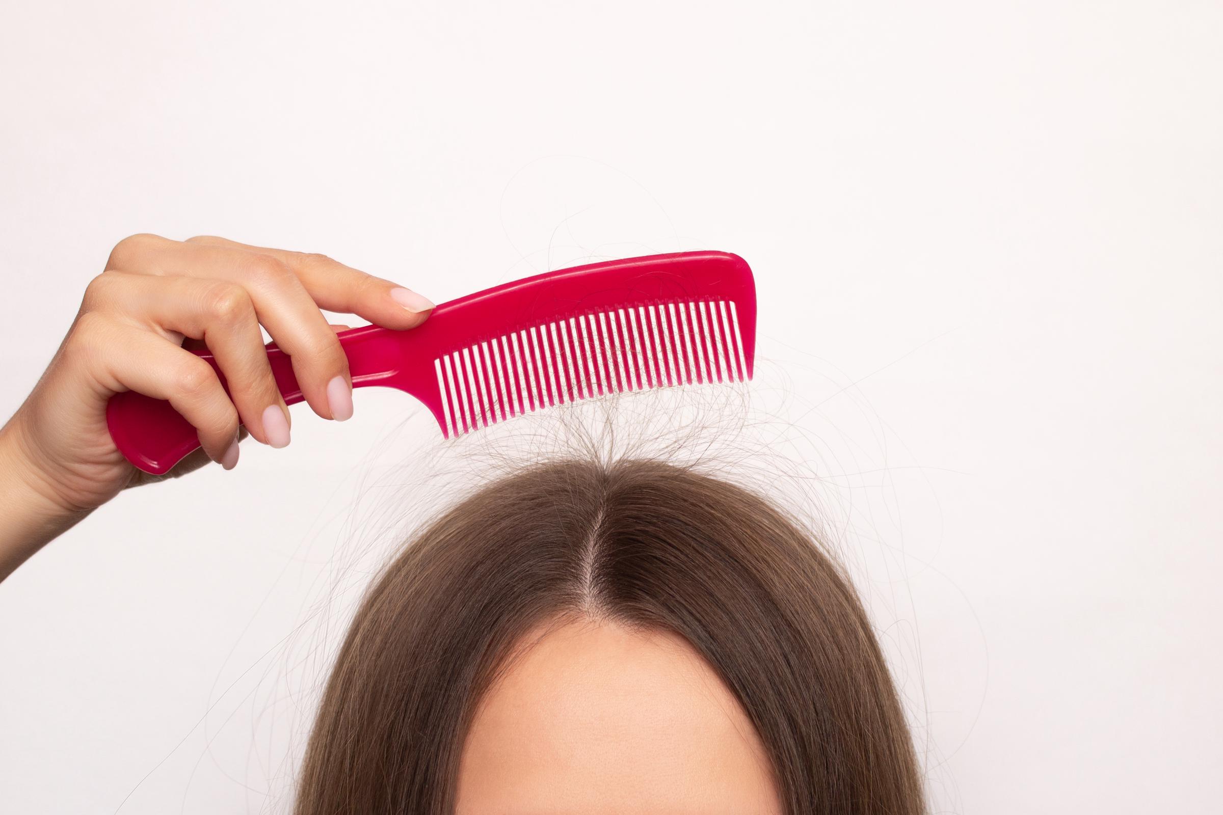 A girl holds a comb to which her hairs attach due to static electricity | Source: Getty Images