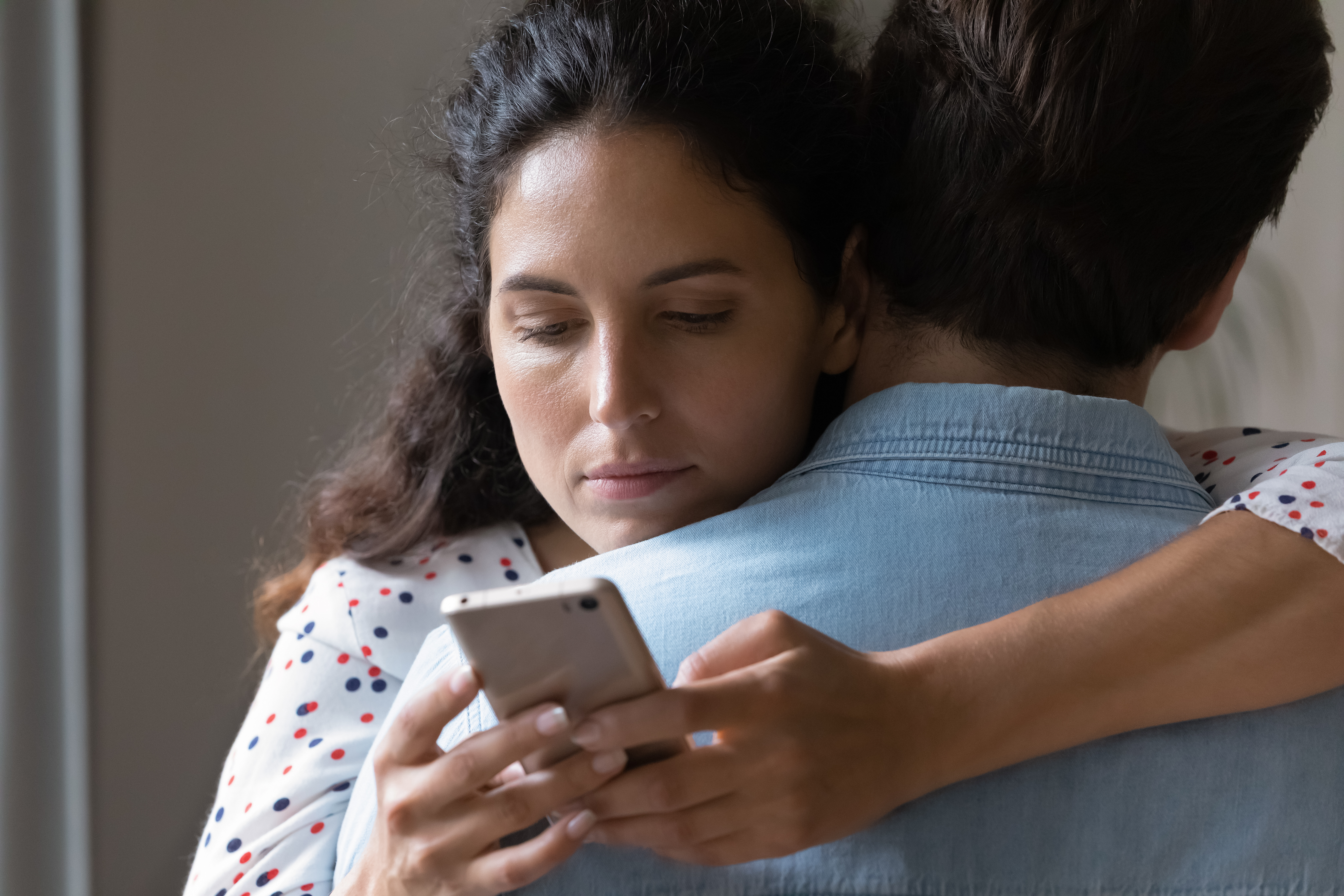 Ein Mann und eine Frau umarmen sich, während sie auf ihr Telefon schaut | Quelle: Shutterstock