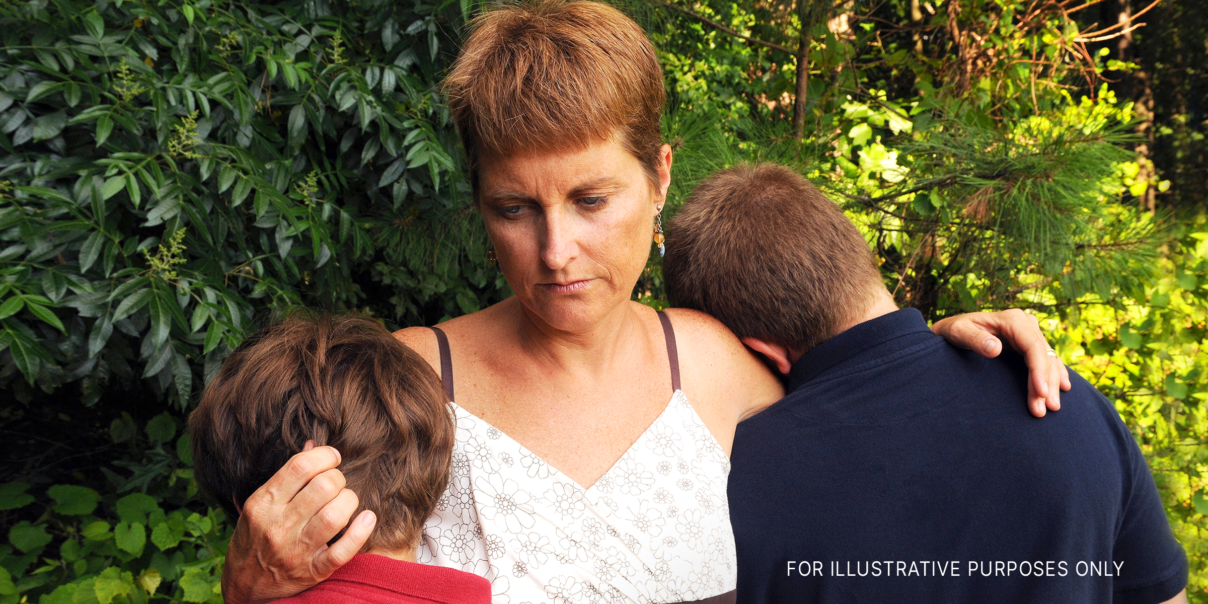A woman hugging two children | Source: Shutterstock