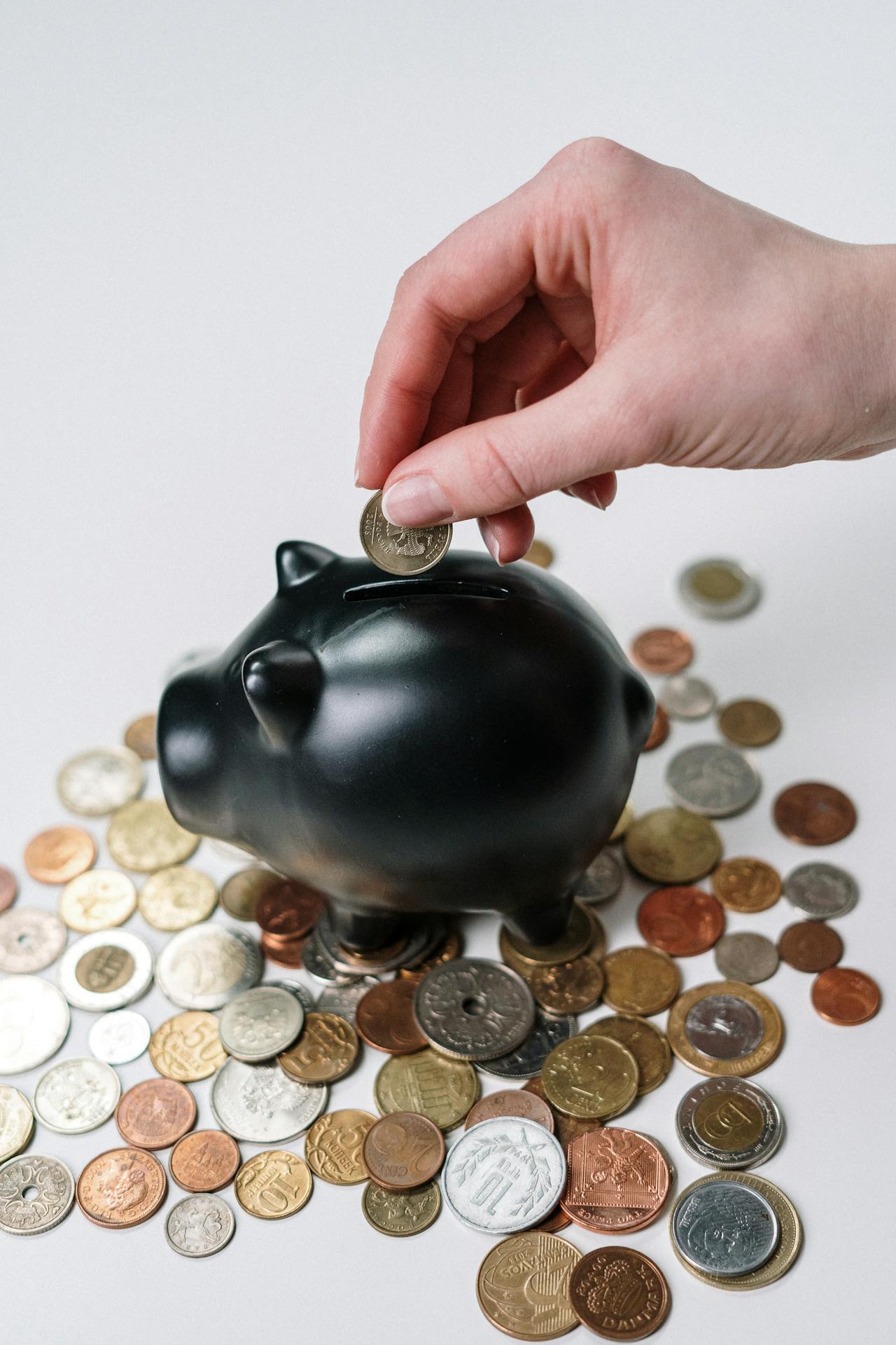 Primer plano de una mujer metiendo una moneda en una hucha | Fuente: Pexels