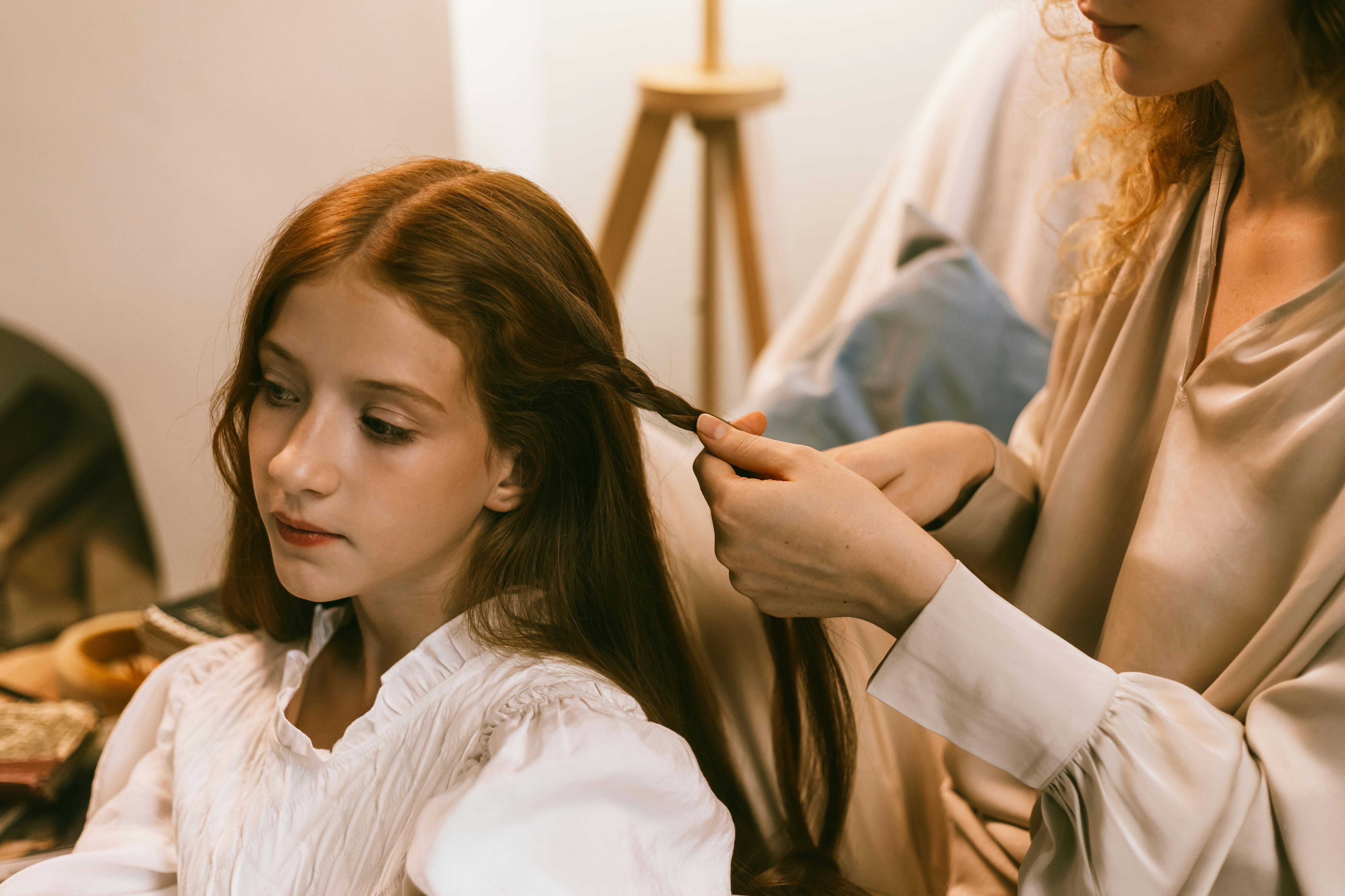 A mother doing her daughter's hair | Source: Pexels